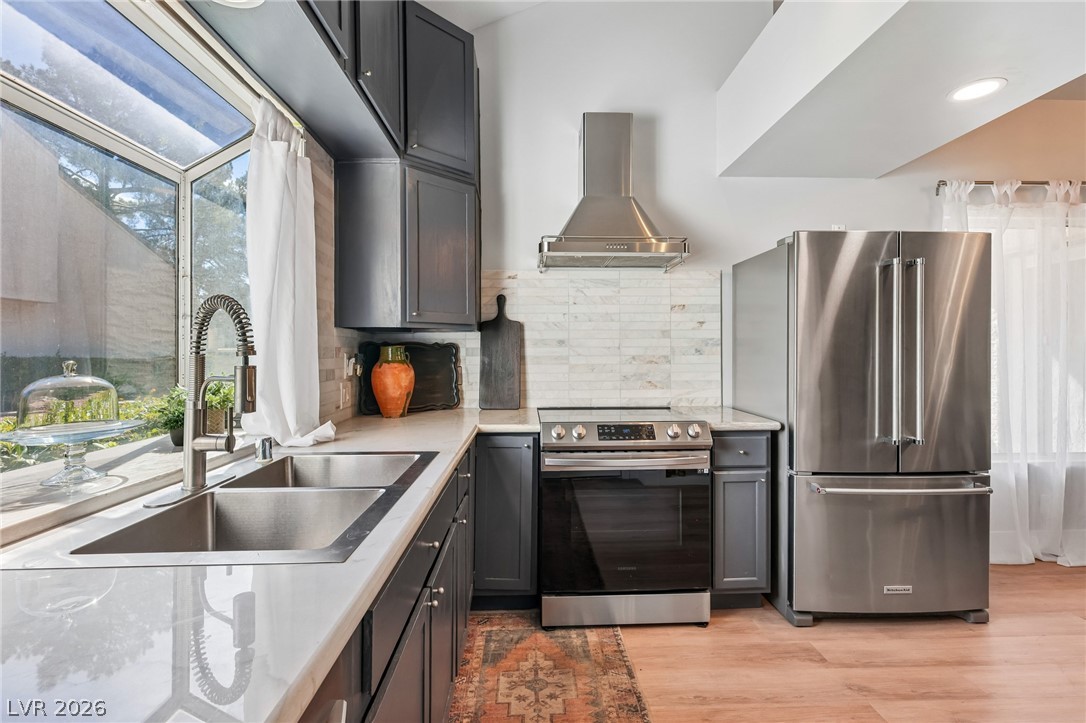 Kitchen with charcoal cabinets, stainless steel appliances, and a double-basin sink by a large window.