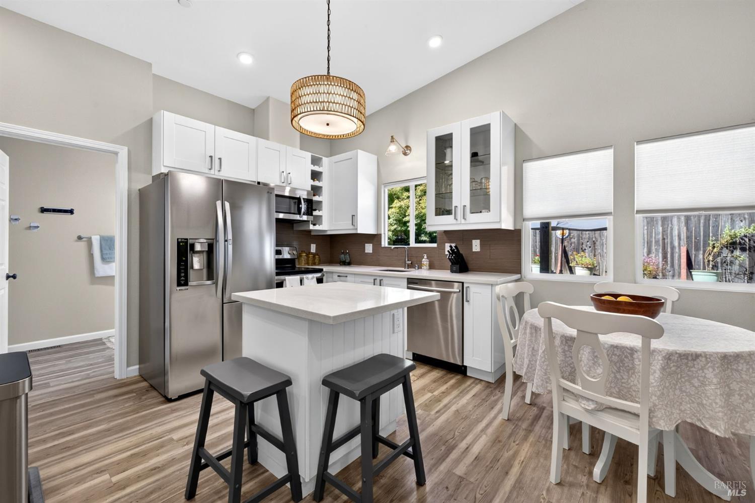 Kitchen with white cabinets, stainless steel appliances, a central island, and an adjacent dining area.