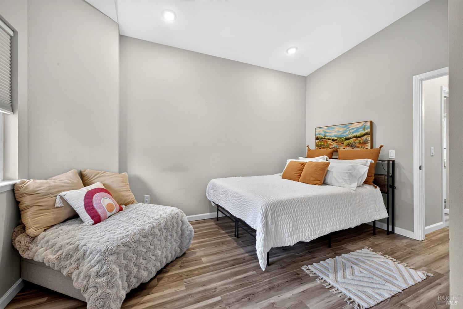 Bedroom with a white bed, rust-colored pillows, and a cushioned bench beside the window.