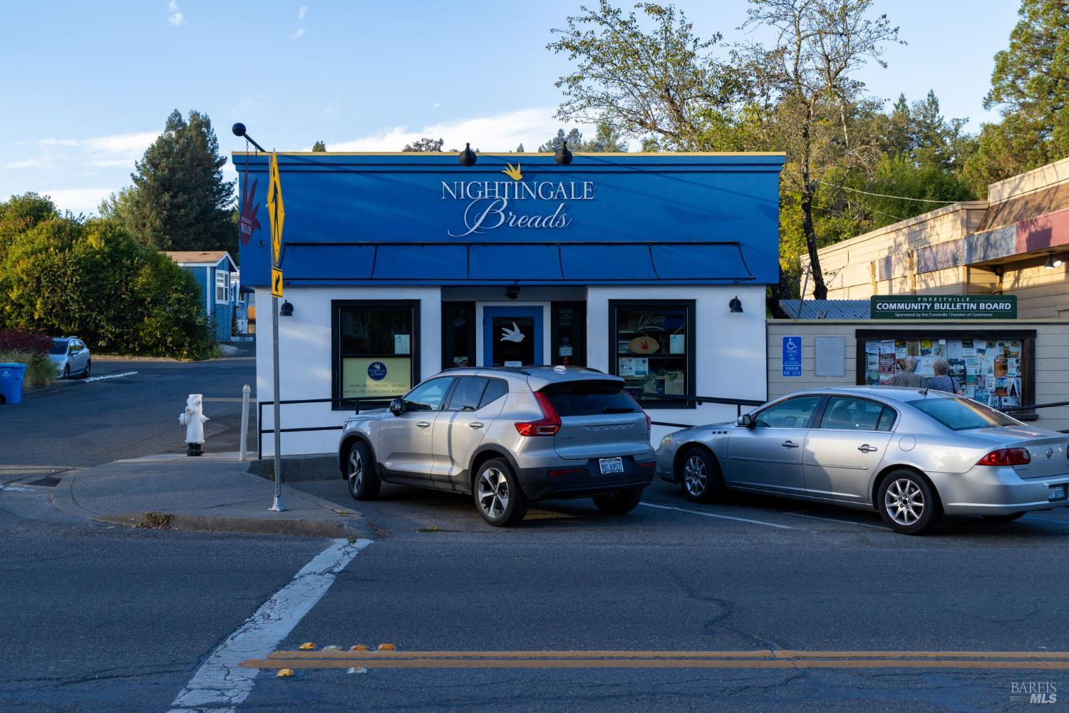 Nightingale Breads bakery storefront with a bright blue facade and community bulletin board nearby.