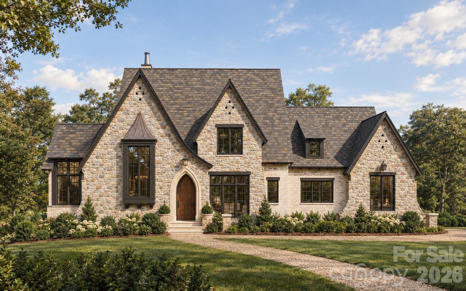 Stone-and-brick home with steep gables, dark-framed windows, landscaped garden, and curving gravel drive.