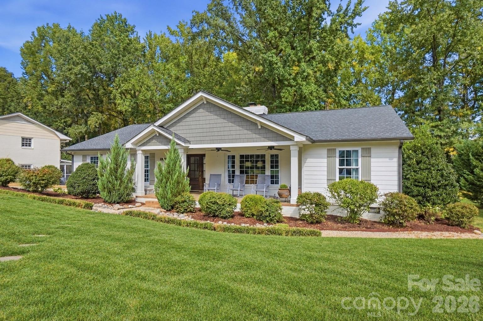 Single-story home with a covered porch, landscaped yard, and broad green lawn.