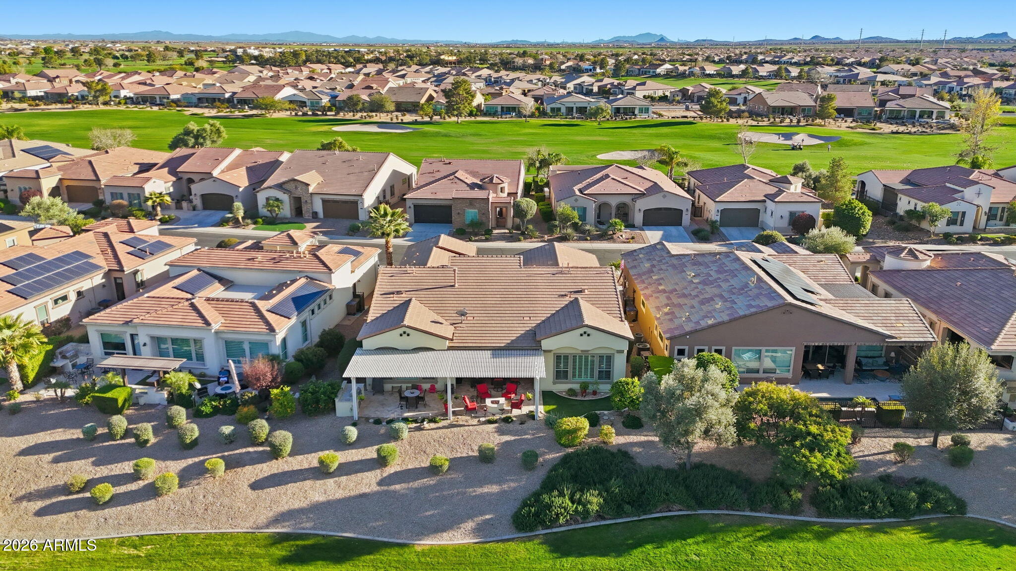 Aerial view of homes bordering a golf course, with distant mountains.