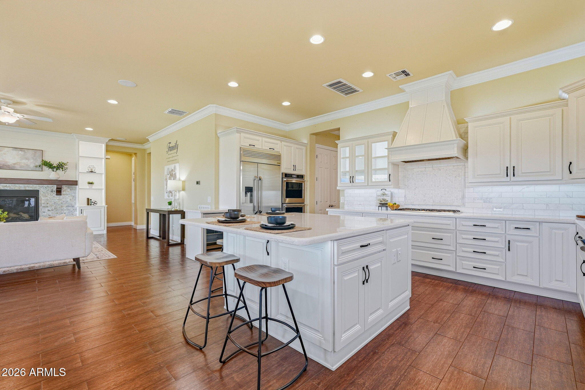 Bright kitchen with a large white island, stainless appliances, and an adjoining living room.
