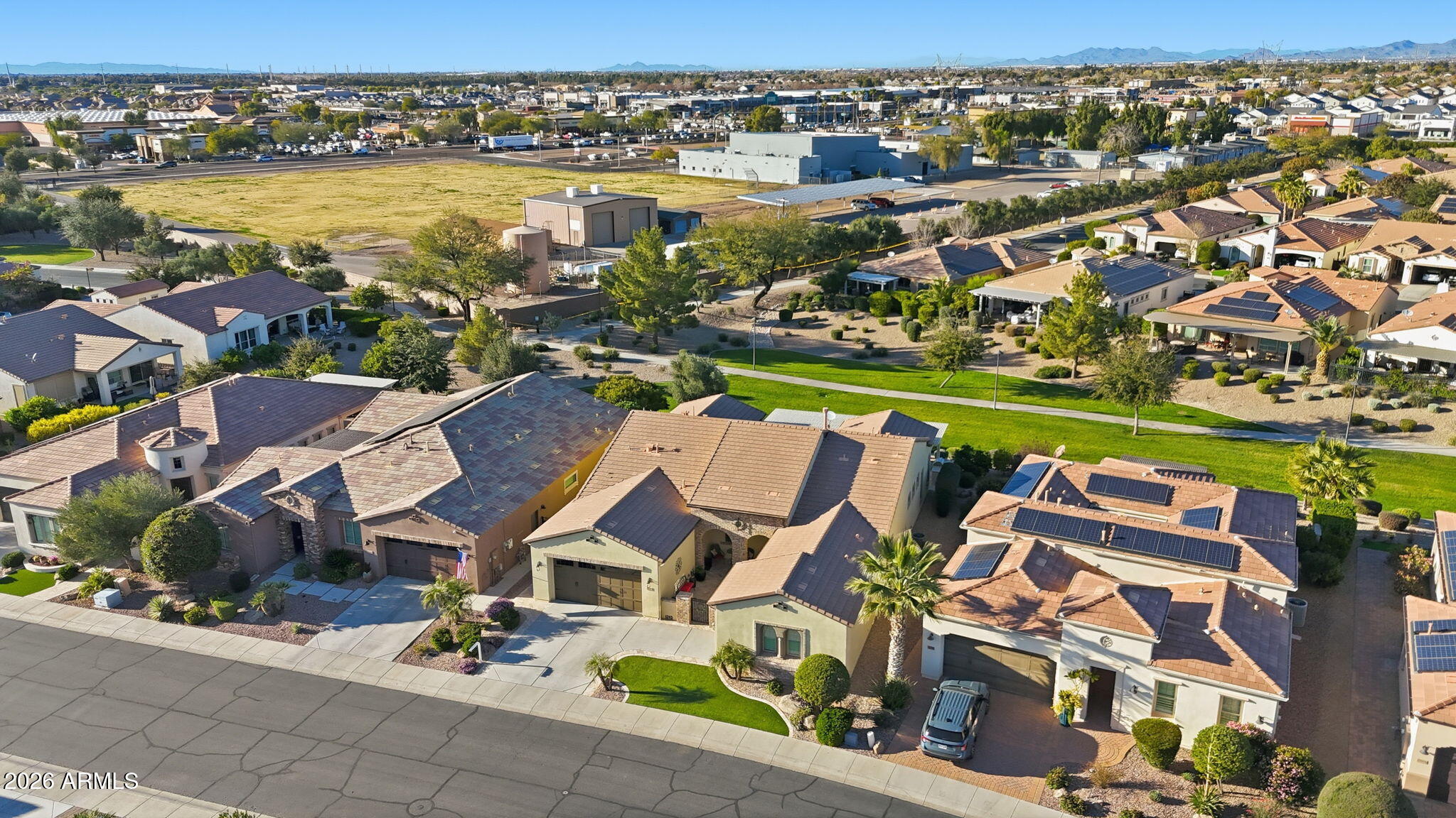 Aerial view of a home and neighborhood, with distant mountains and commercial buildings.