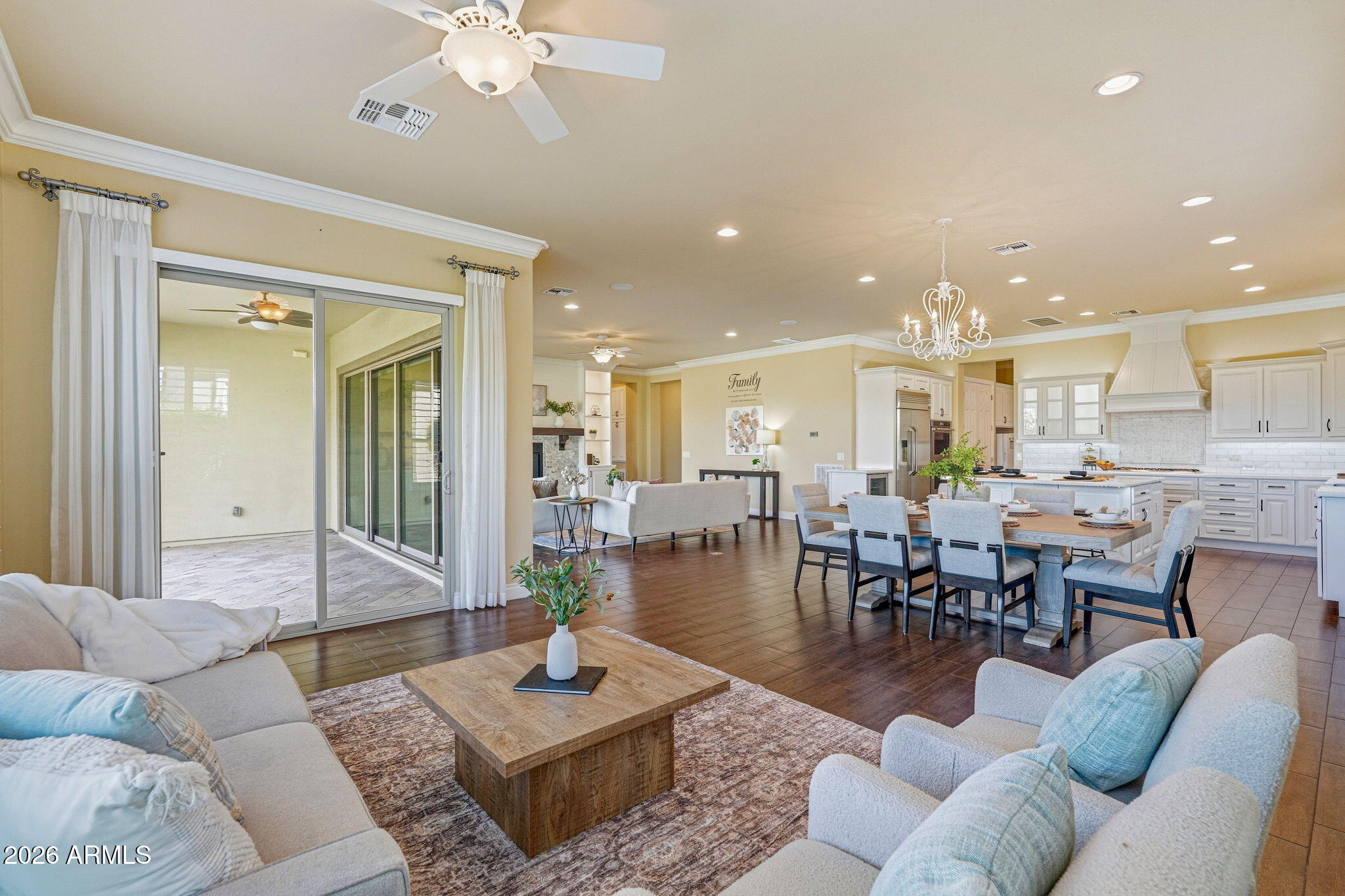 Open-plan living room with a dining area and white kitchen, featuring sliding glass doors to a patio.