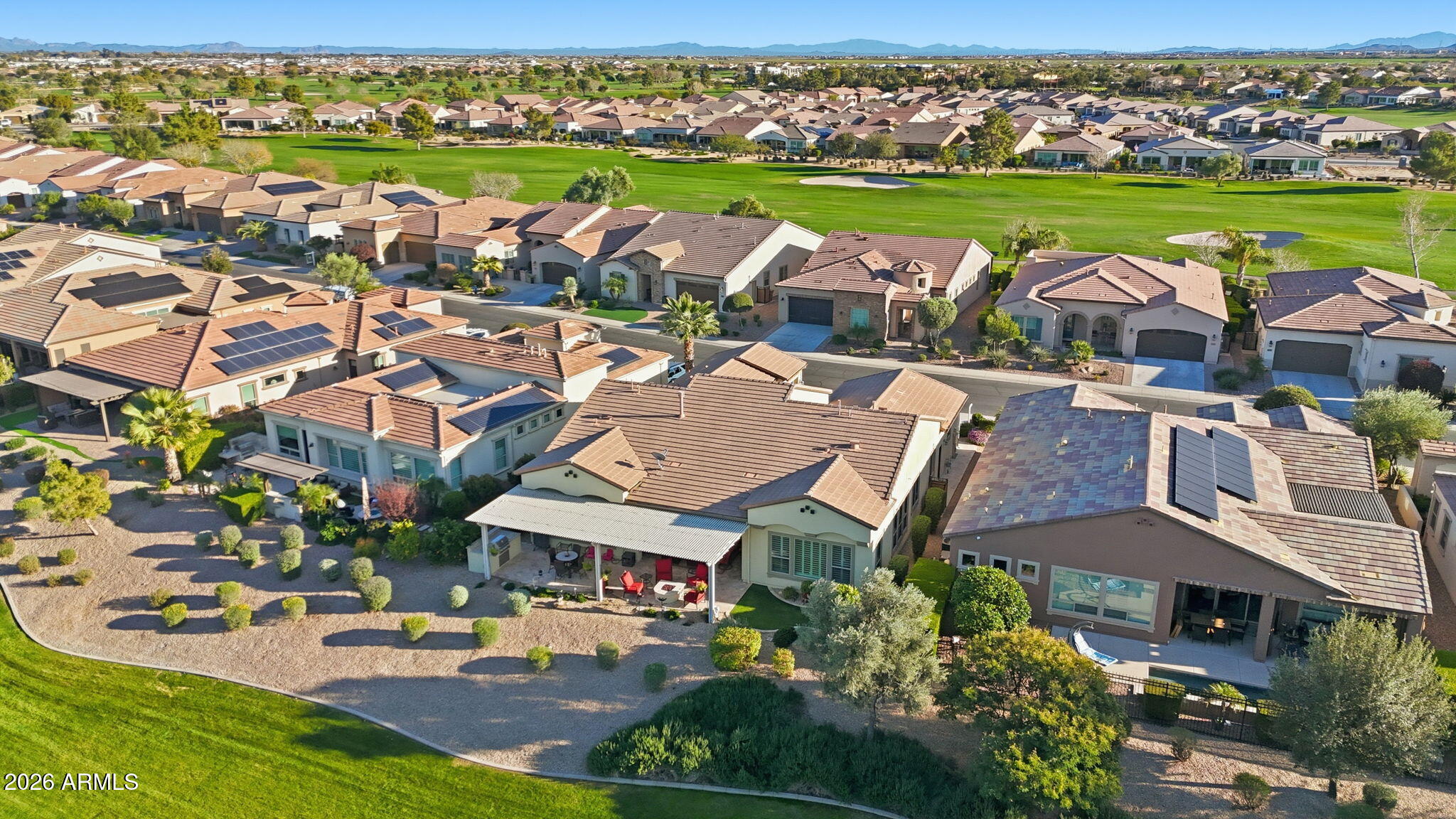 Aerial view of homes beside a golf course, with mountains on the horizon.