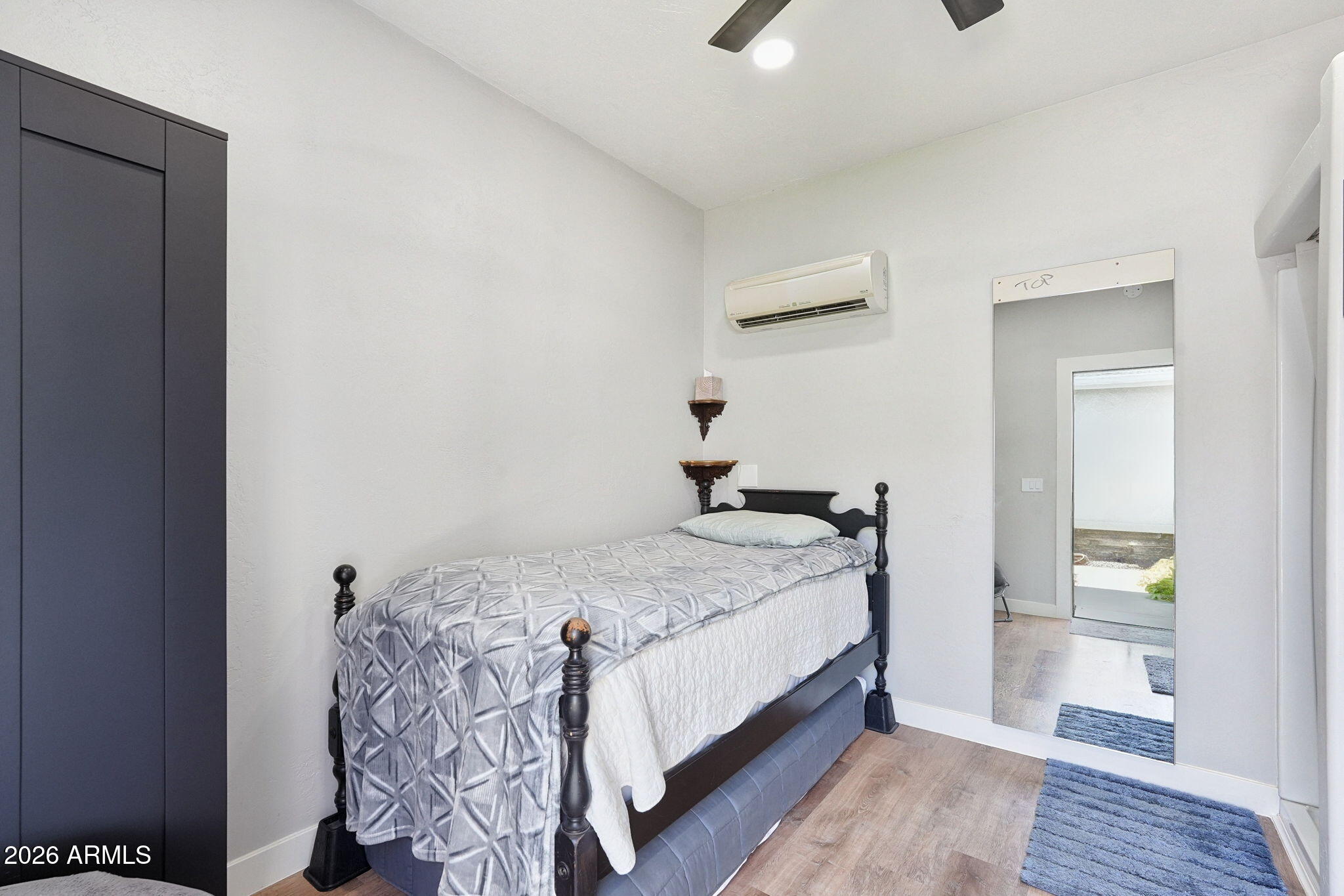 Bedroom with a dark four-poster bed, gray patterned bedding, and mirrored closet doors.