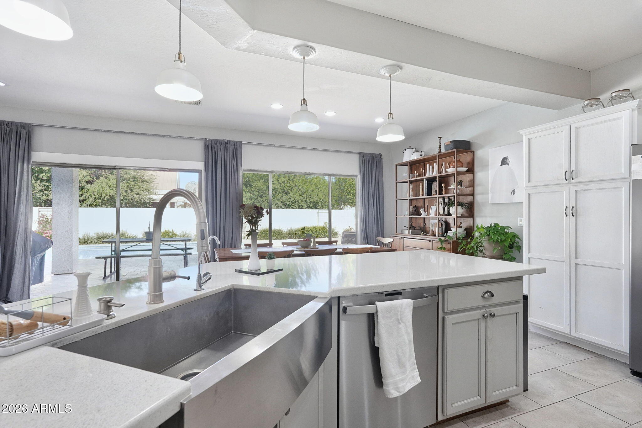 Kitchen with a large island and deep sink, opening through sliding doors to a backyard pool.