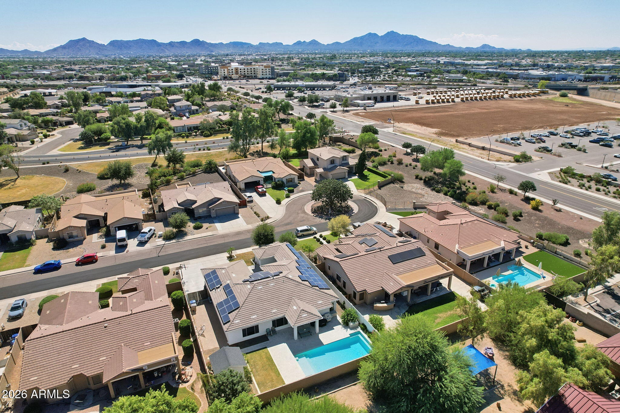 Aerial view of a home with a backyard pool, solar panels, and distant mountains.