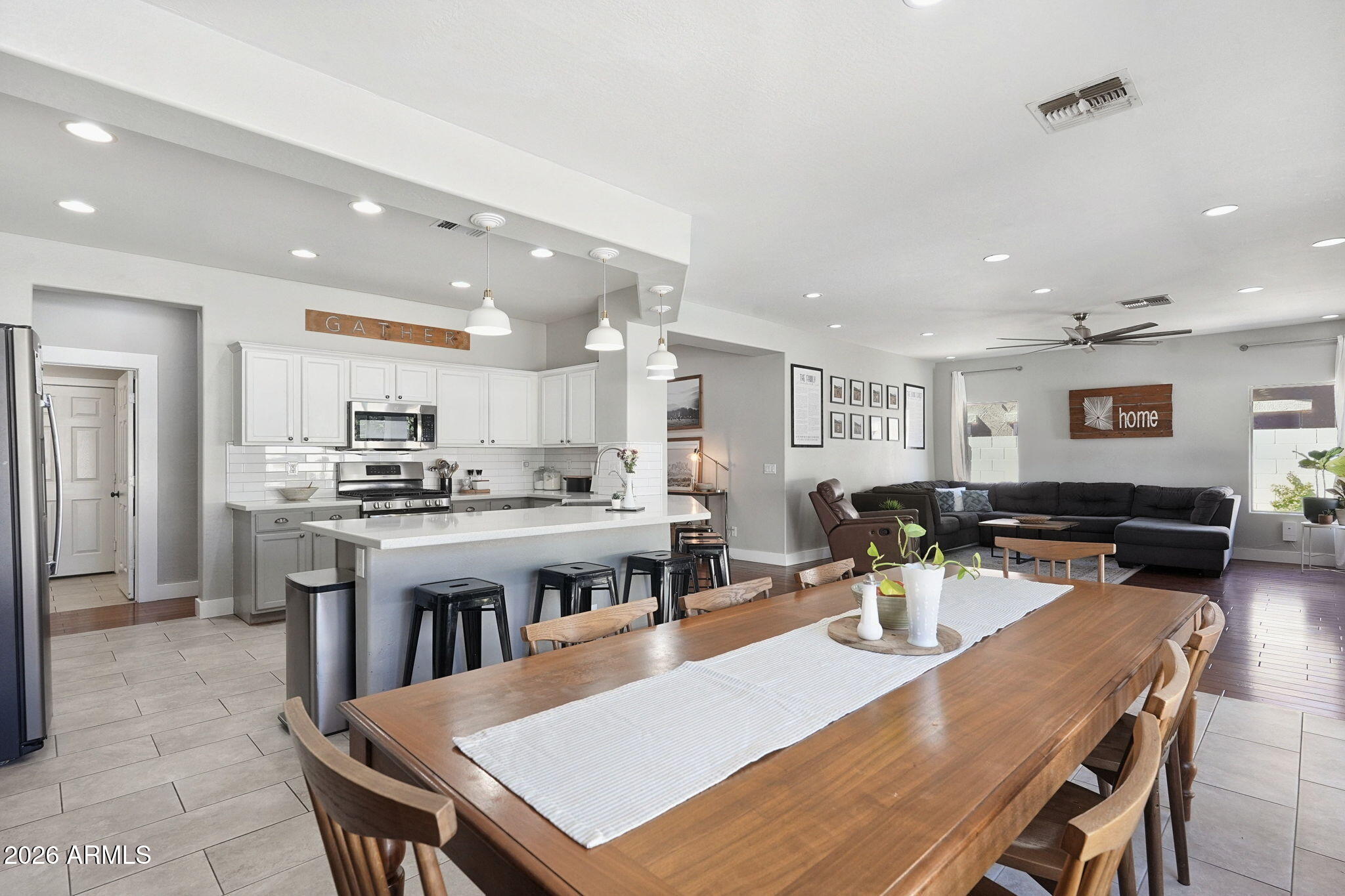 Open-plan kitchen, dining area, and living room with white cabinetry, island, and long wood table.