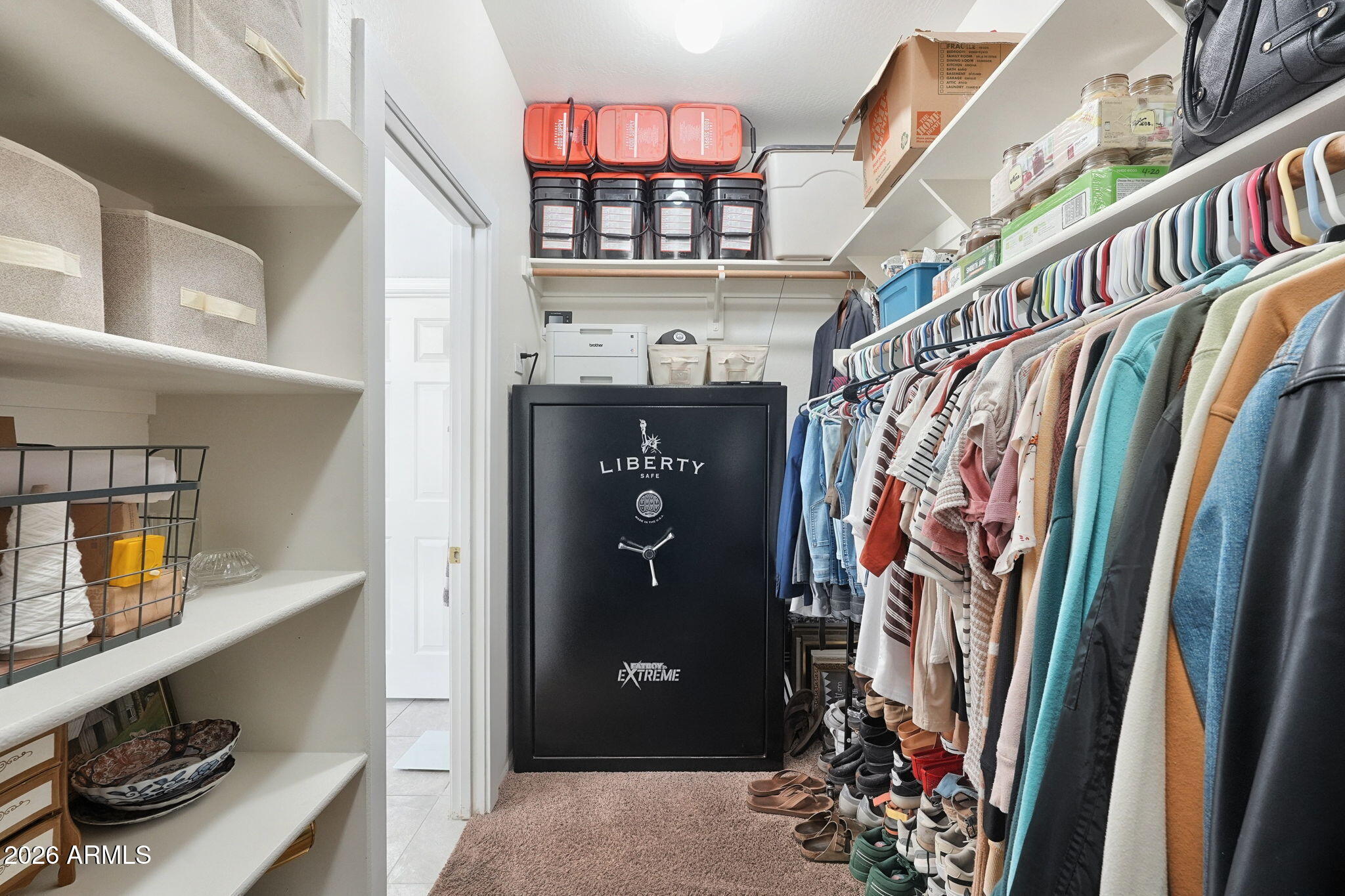 Walk-in closet with extensive clothing and shoe storage and a large black safe.