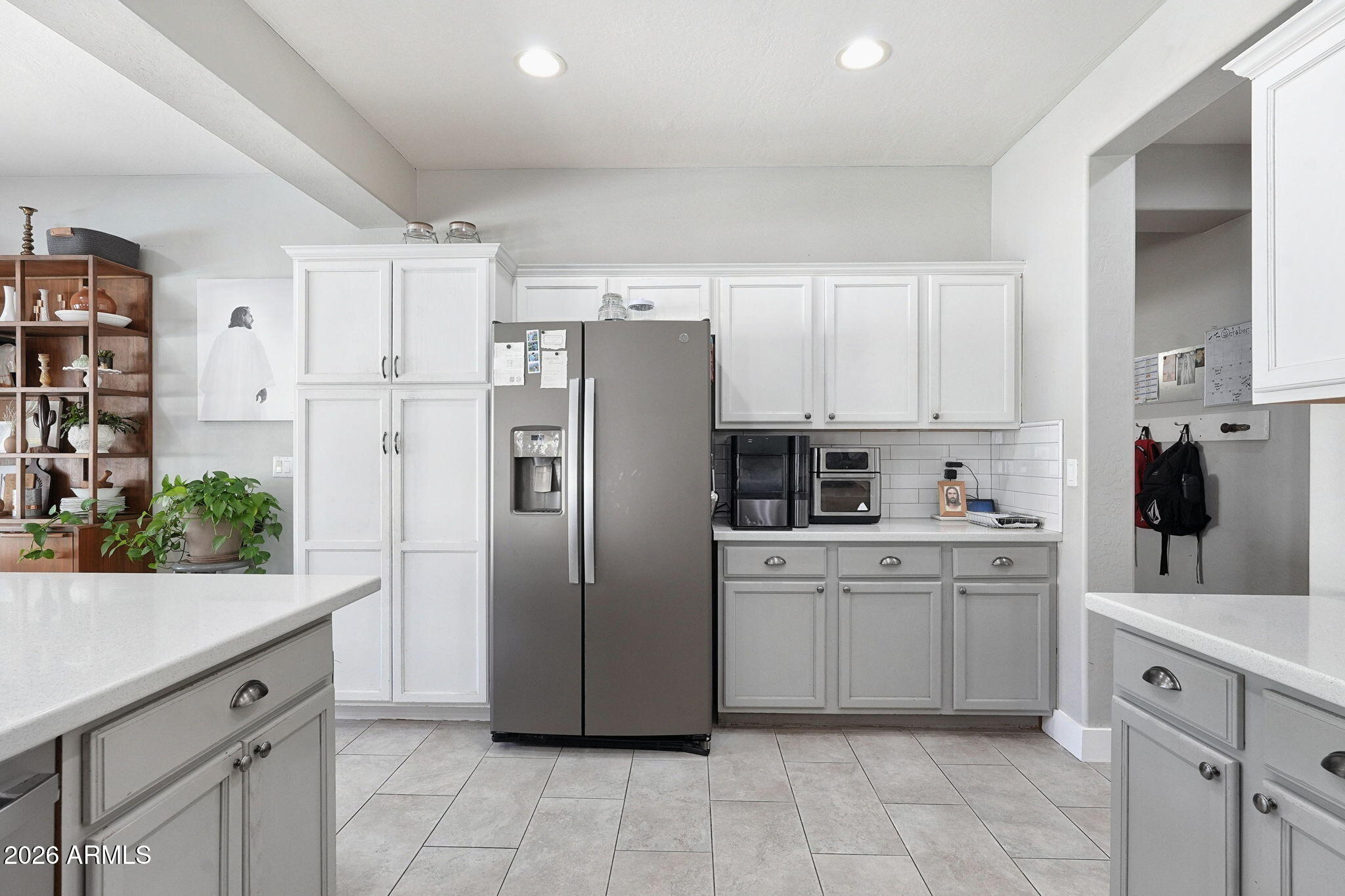 Kitchen with white paneled cabinets, stainless-steel refrigerator, and gray countertops.
