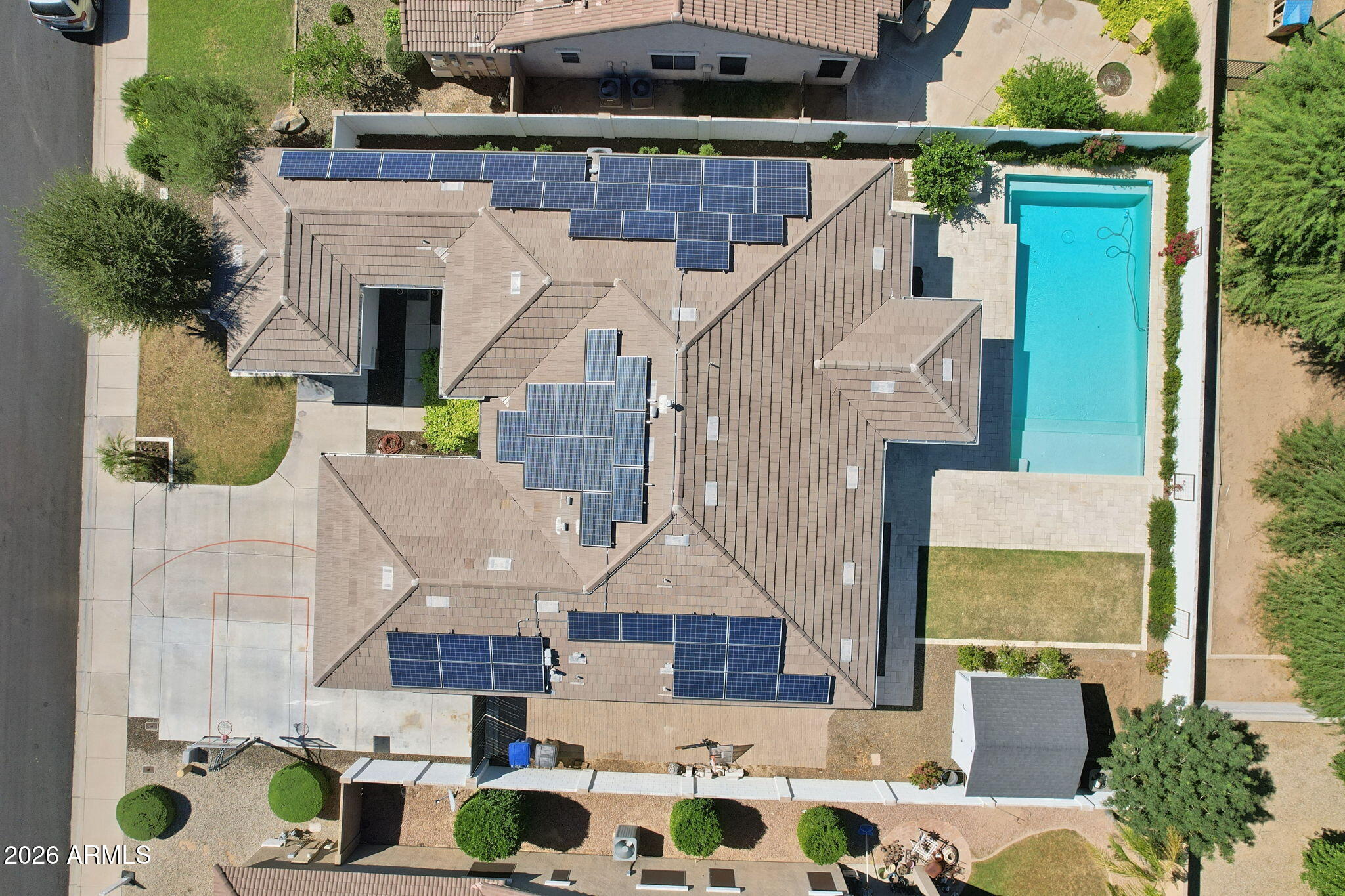 Aerial view of a home with extensive rooftop solar panels and a backyard pool.