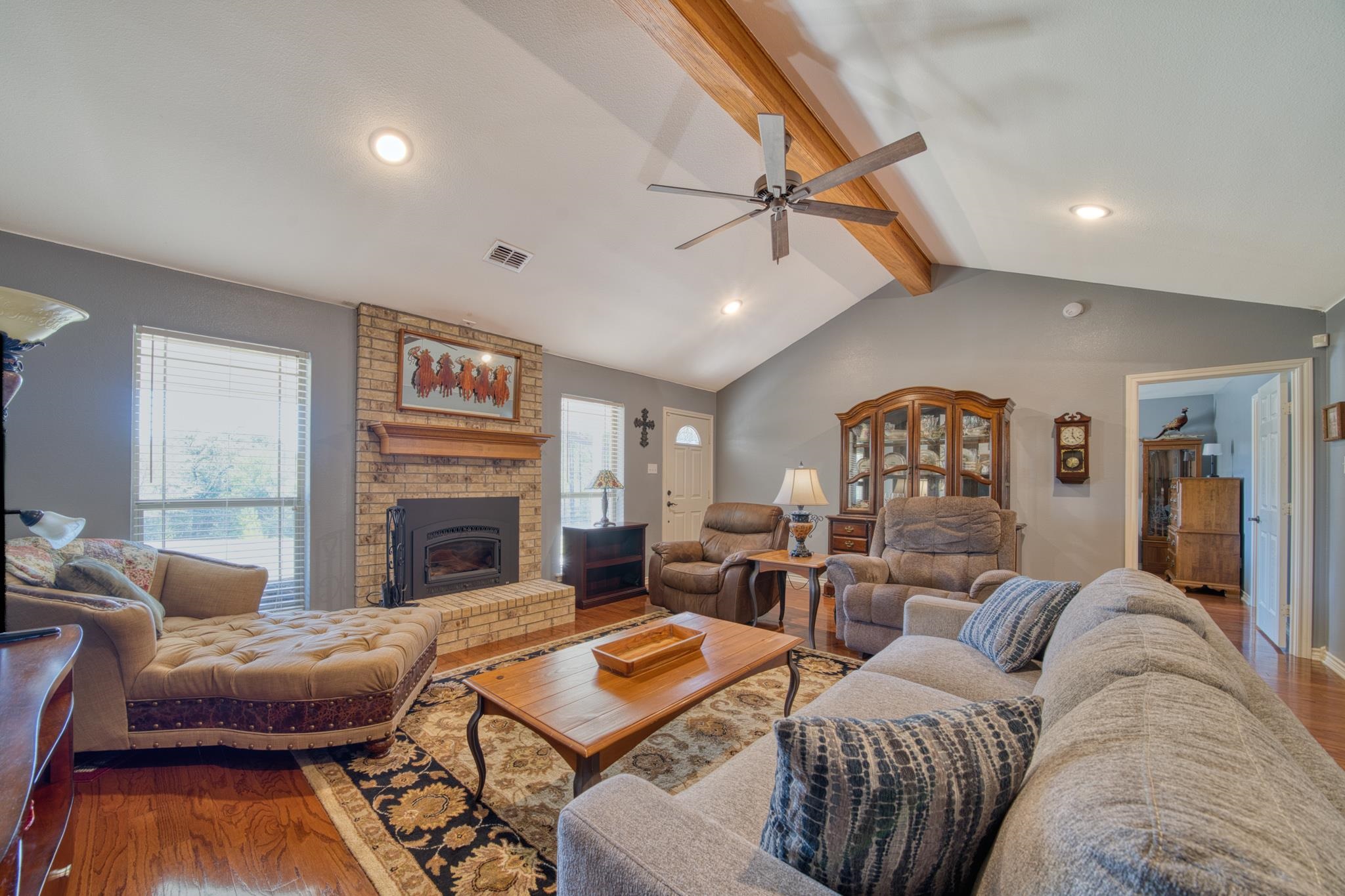 Living room with a vaulted ceiling, exposed wood beam, and brick fireplace.