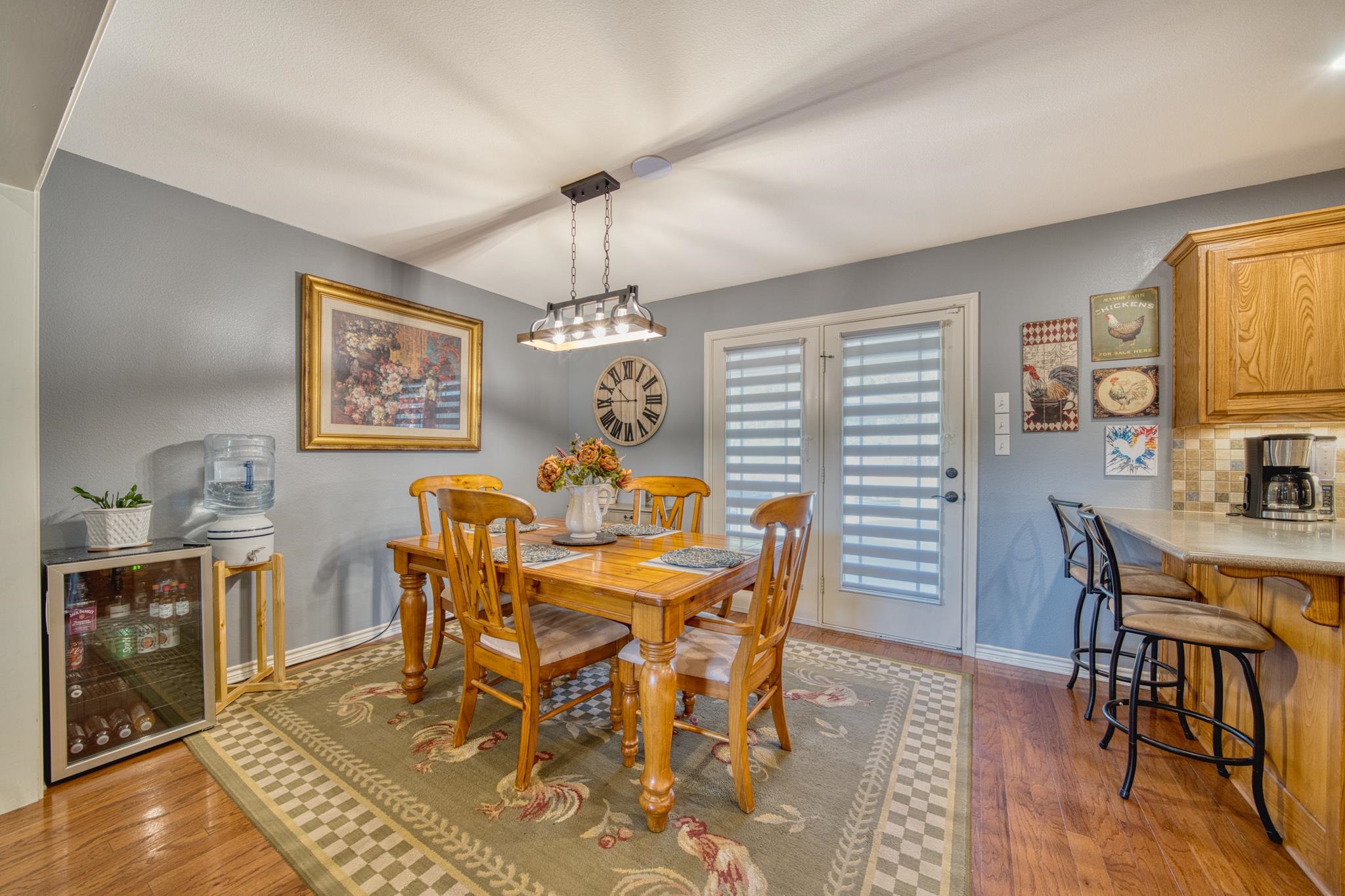 Dining area with a wooden table and chairs on a patterned rug beside the kitchen counter.