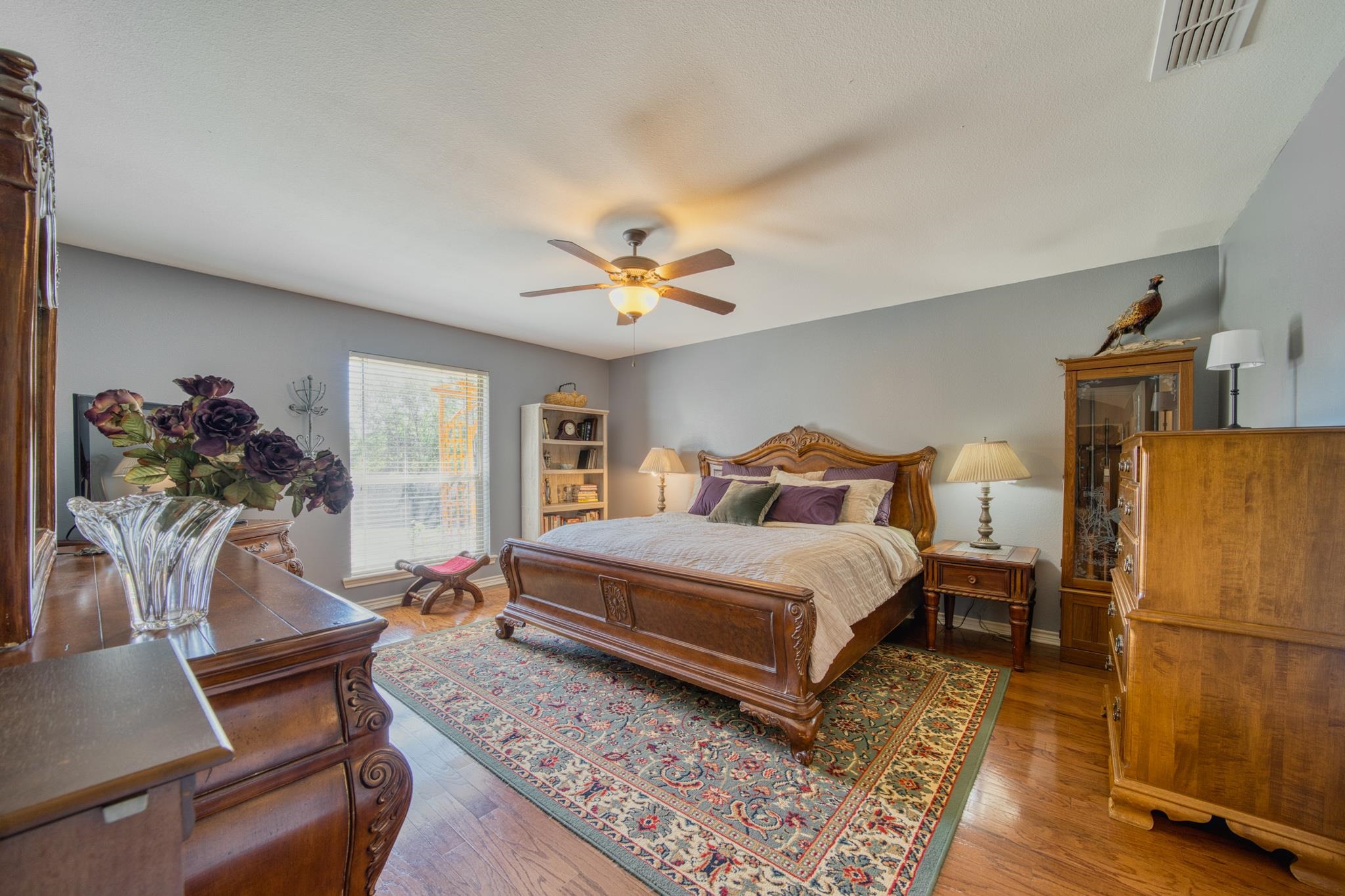 Bedroom with a carved wooden bed, matching furniture, and a large patterned rug.