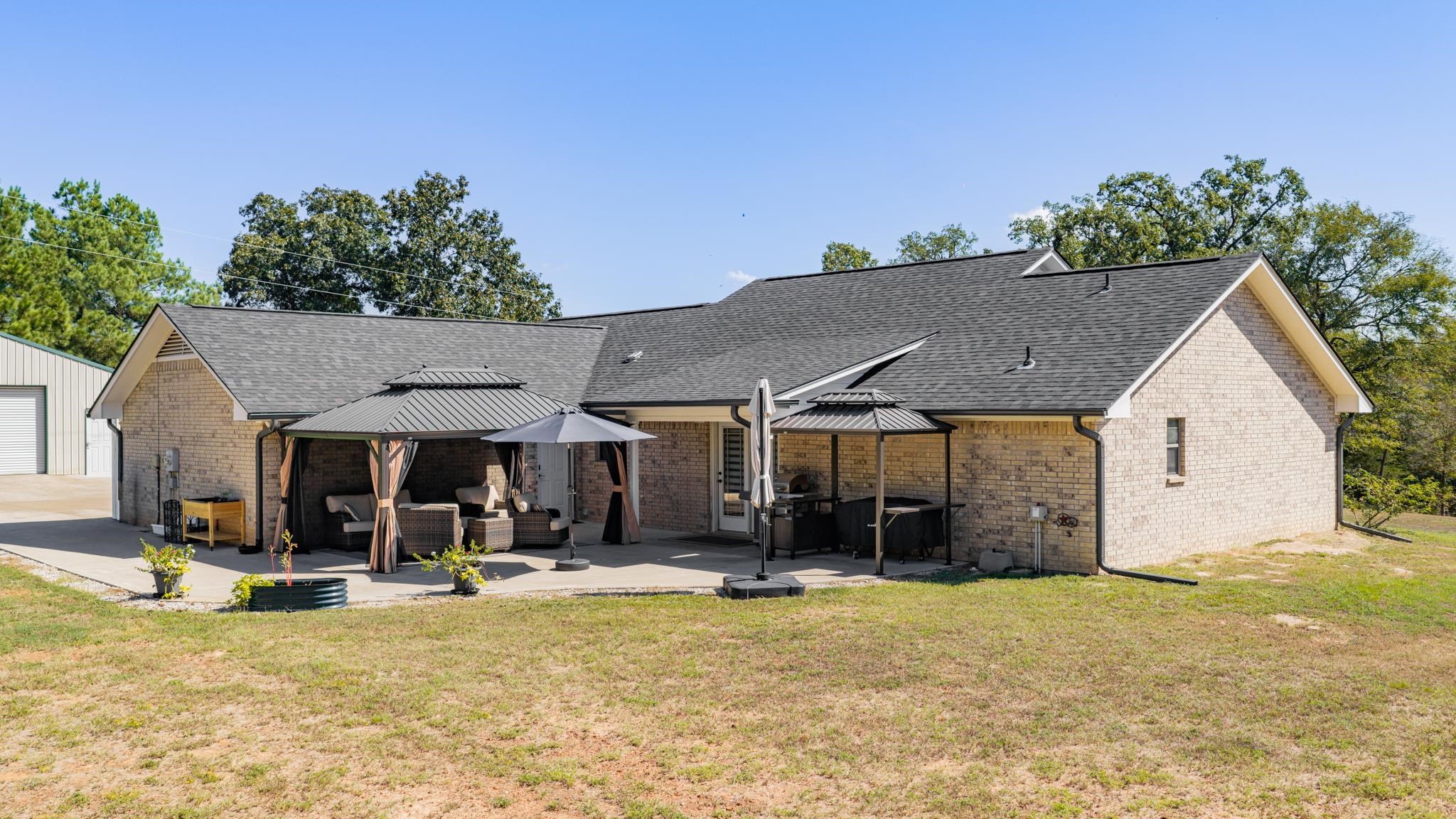 Tan brick home with a broad patio, covered seating areas, and outdoor kitchen.