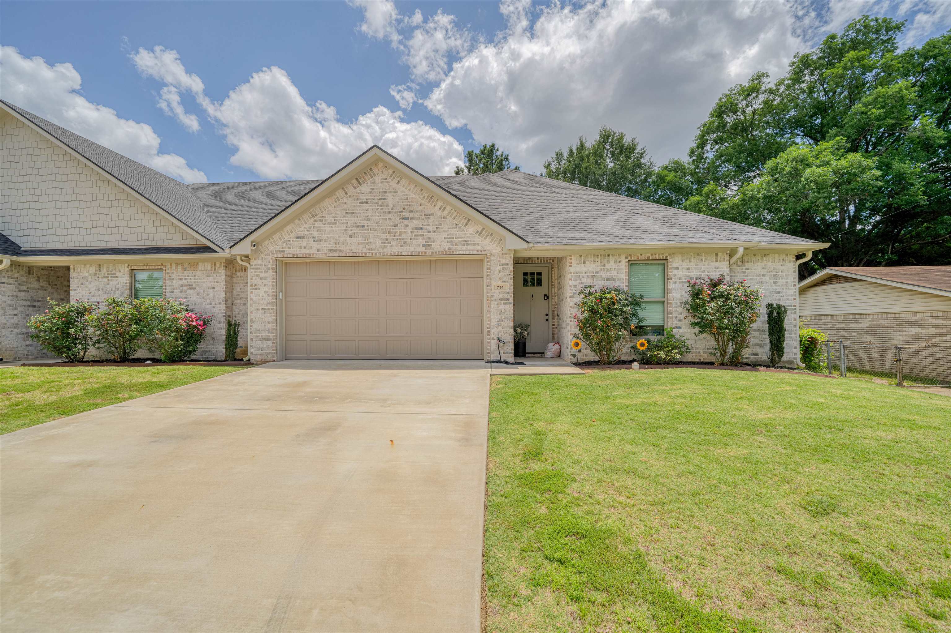 Single-story brick house with an attached garage, wide driveway, and landscaped front lawn.
