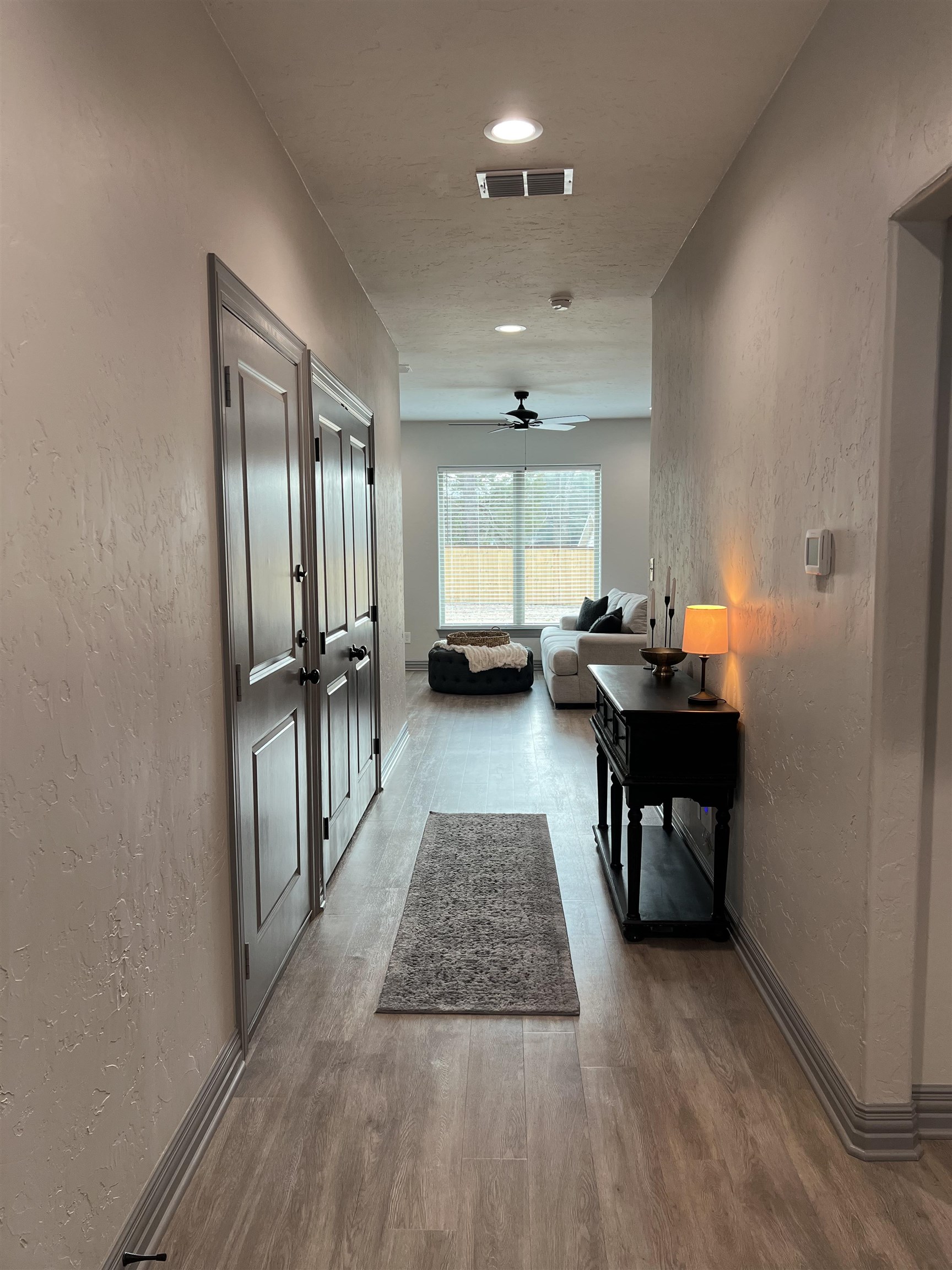 Entry hallway leading to a living room, with paneled doors and a dark console table.