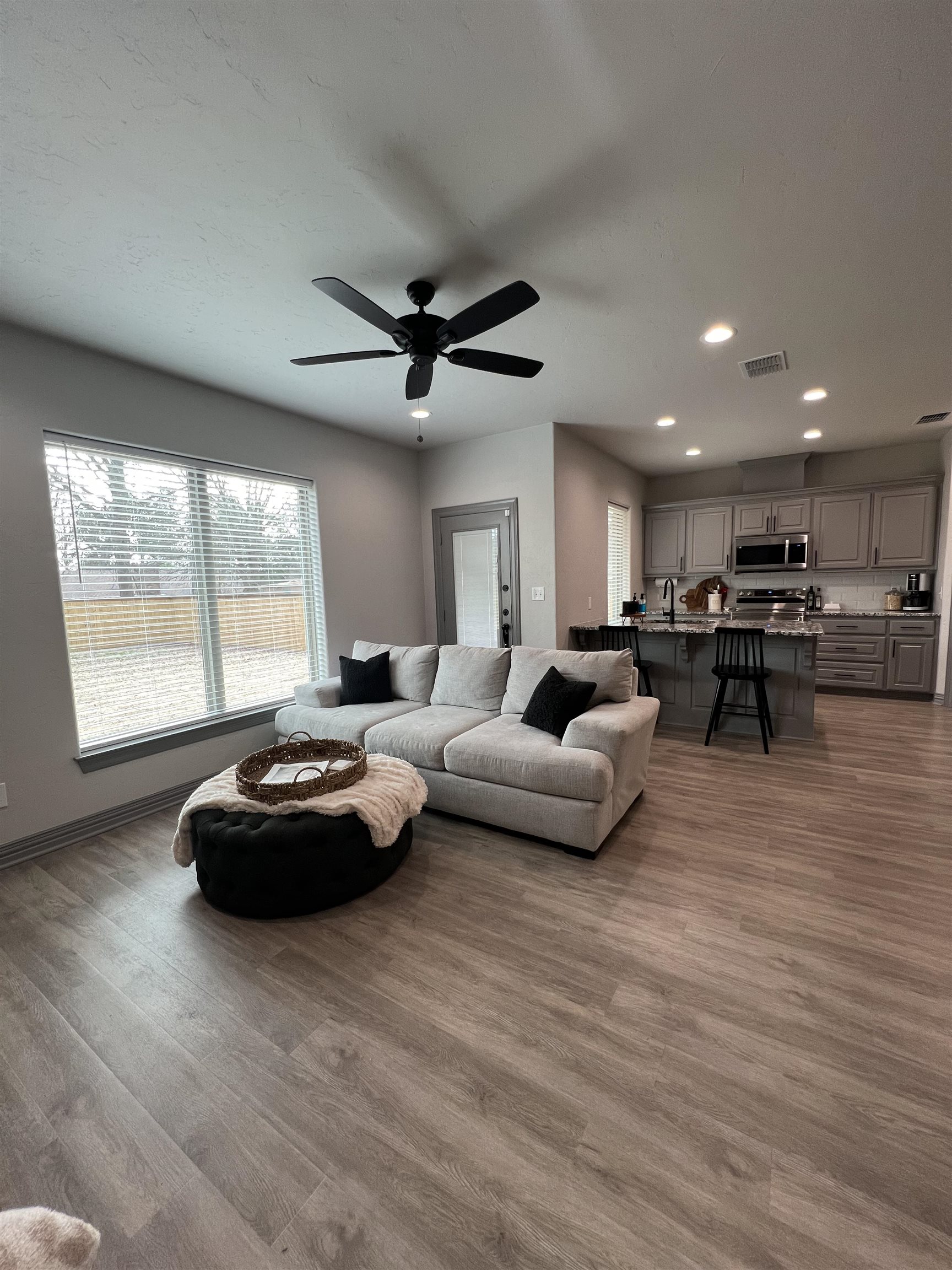 Open-plan living room and kitchen with a light sectional, large window, and kitchen island.