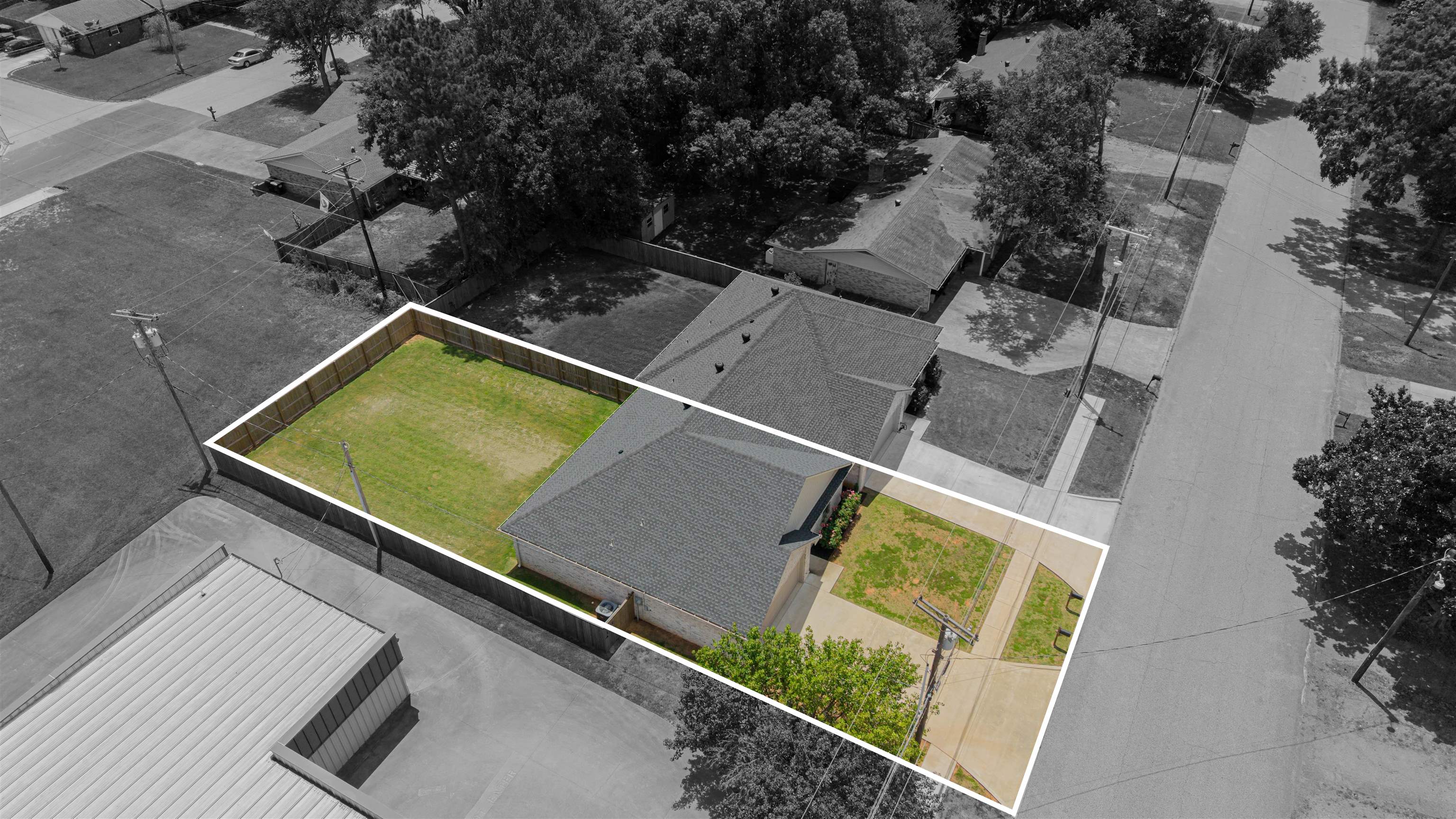 Aerial view of a brick house and fenced lawn, with the property outlined in white.