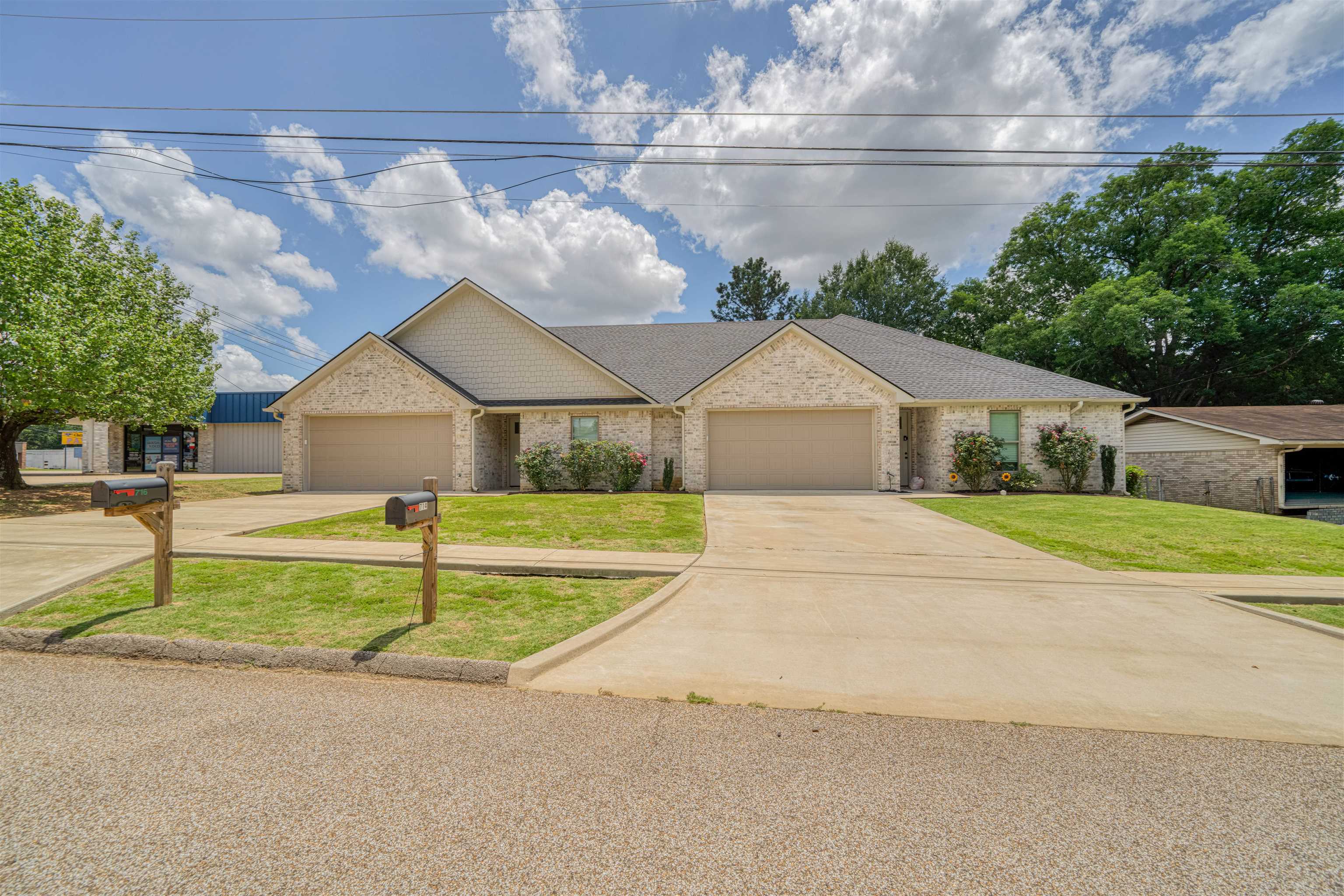Light brick duplex with two garages, separate driveways, and mailboxes at the curb.