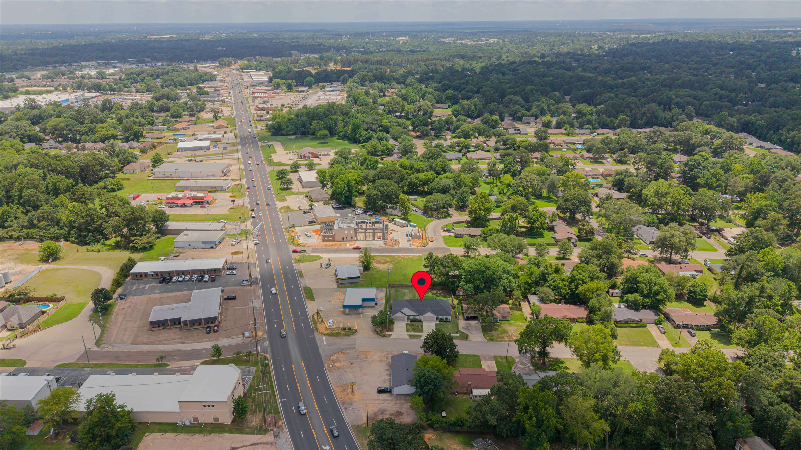 Aerial view of the marked home among leafy streets near a major road and commercial buildings.