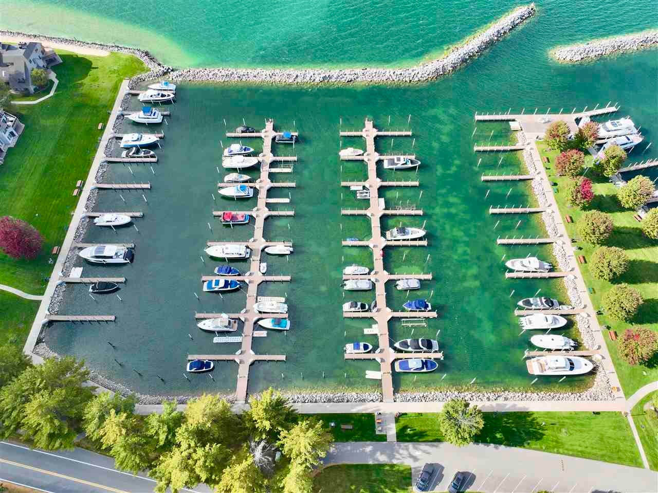 Aerial view of a marina with boats along the docks inside a curved rock breakwater.