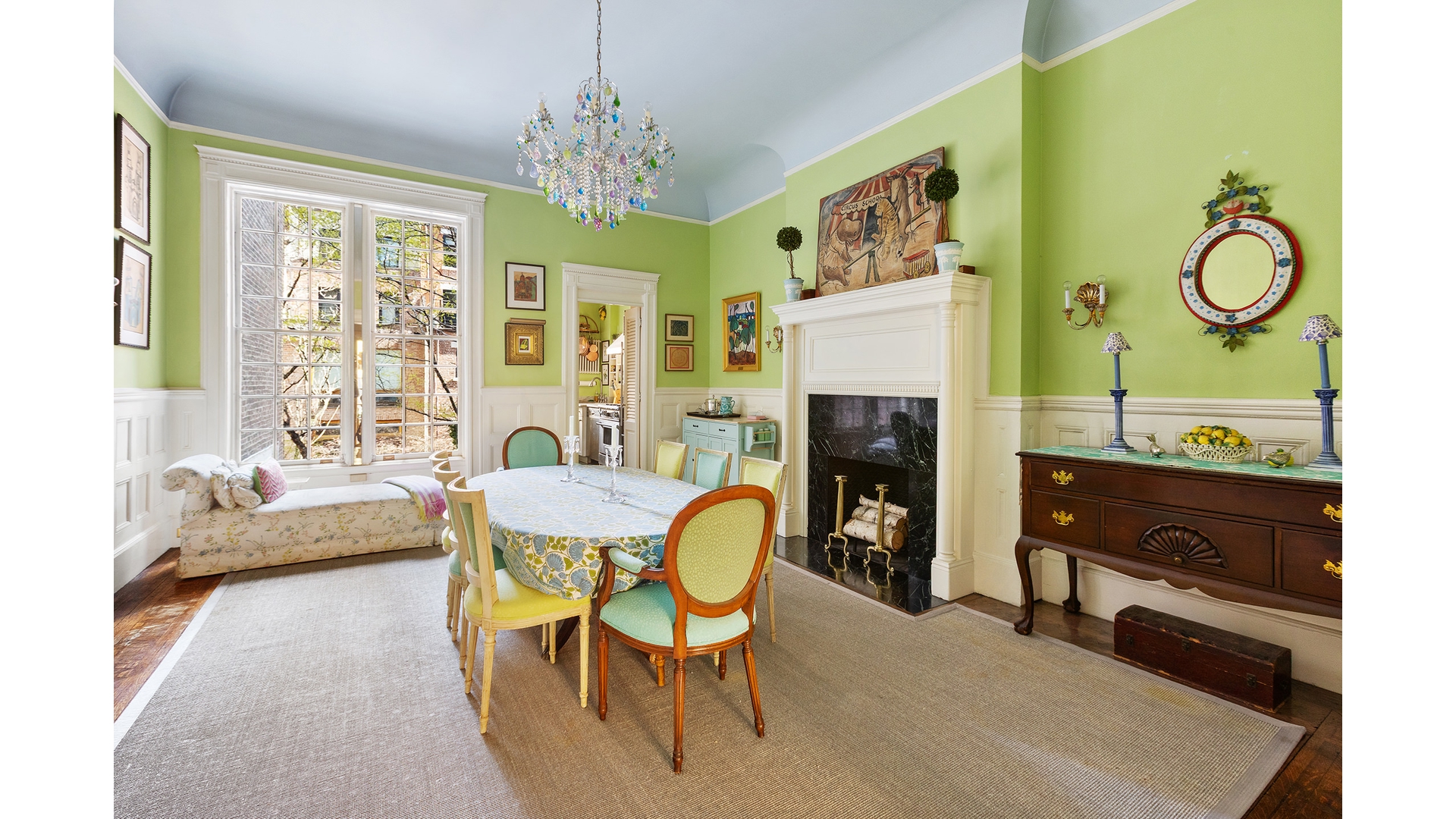 Dining room with a crystal chandelier, tall windows, lime-green walls, and a white fireplace.