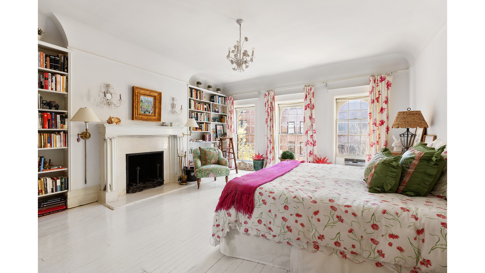 Bright bedroom with a white fireplace, built-in bookshelves, and floral bedding.