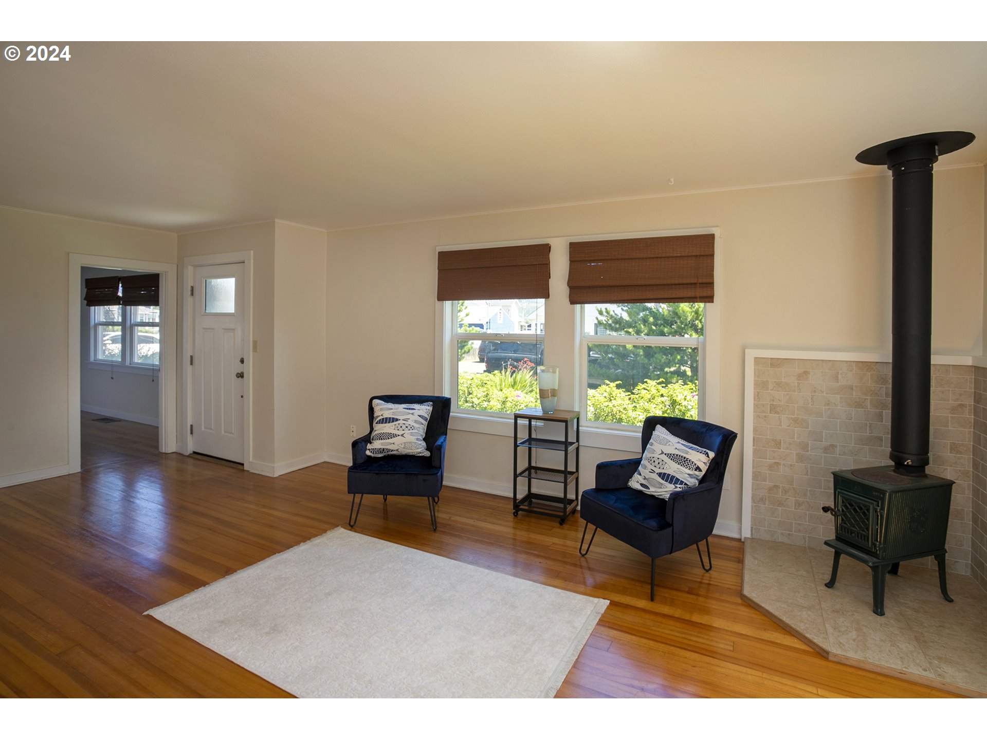Living room with navy armchairs, hardwood floors, and a freestanding wood stove.
