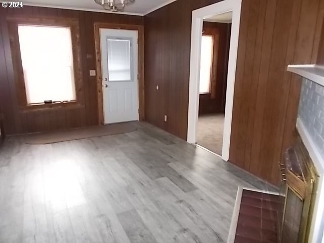 Empty wood-paneled room with gray plank flooring and a tiled fireplace hearth.