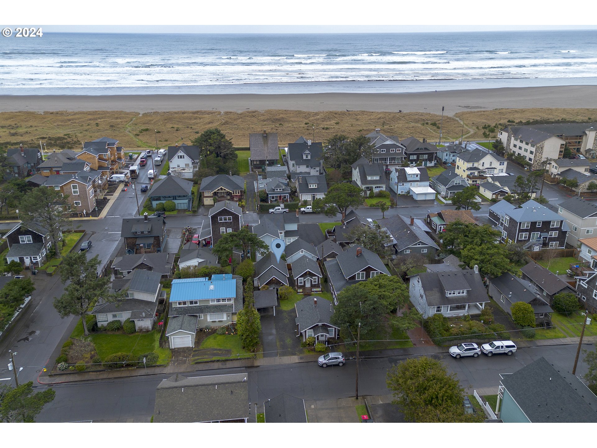 Aerial view of a coastal neighborhood, with the beach and ocean beyond the homes.