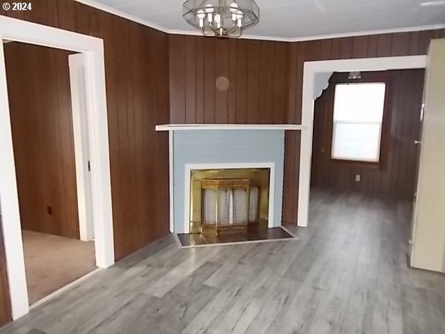 Unfurnished wood-paneled room with a central fireplace, gray plank flooring, and a ceiling light.