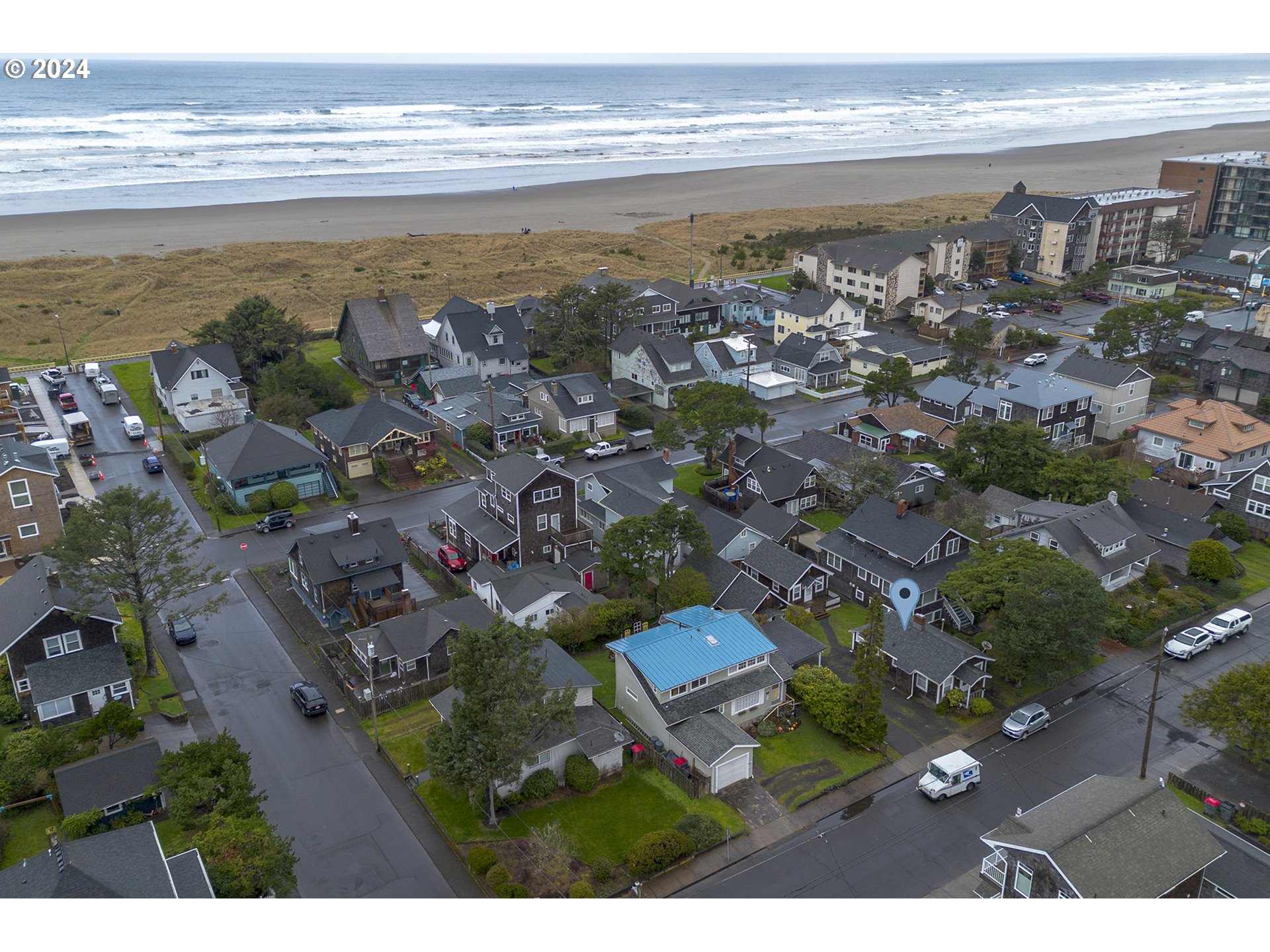 Aerial view of a Seaside neighborhood, with a map pin among homes beside the beach and ocean.