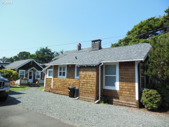 Single-story cedar-shingle house with a gray roof and gravel driveway.