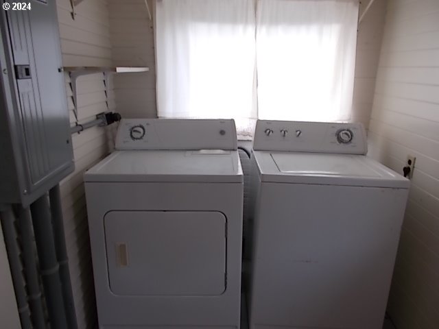 Laundry room with a white washer and dryer beneath a bright window.