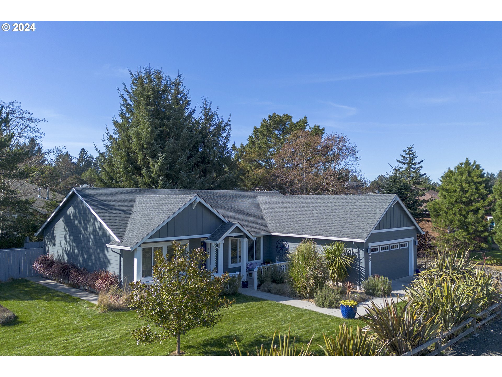 Gray single-story home with multiple gables, an attached garage, and landscaped front yard.
