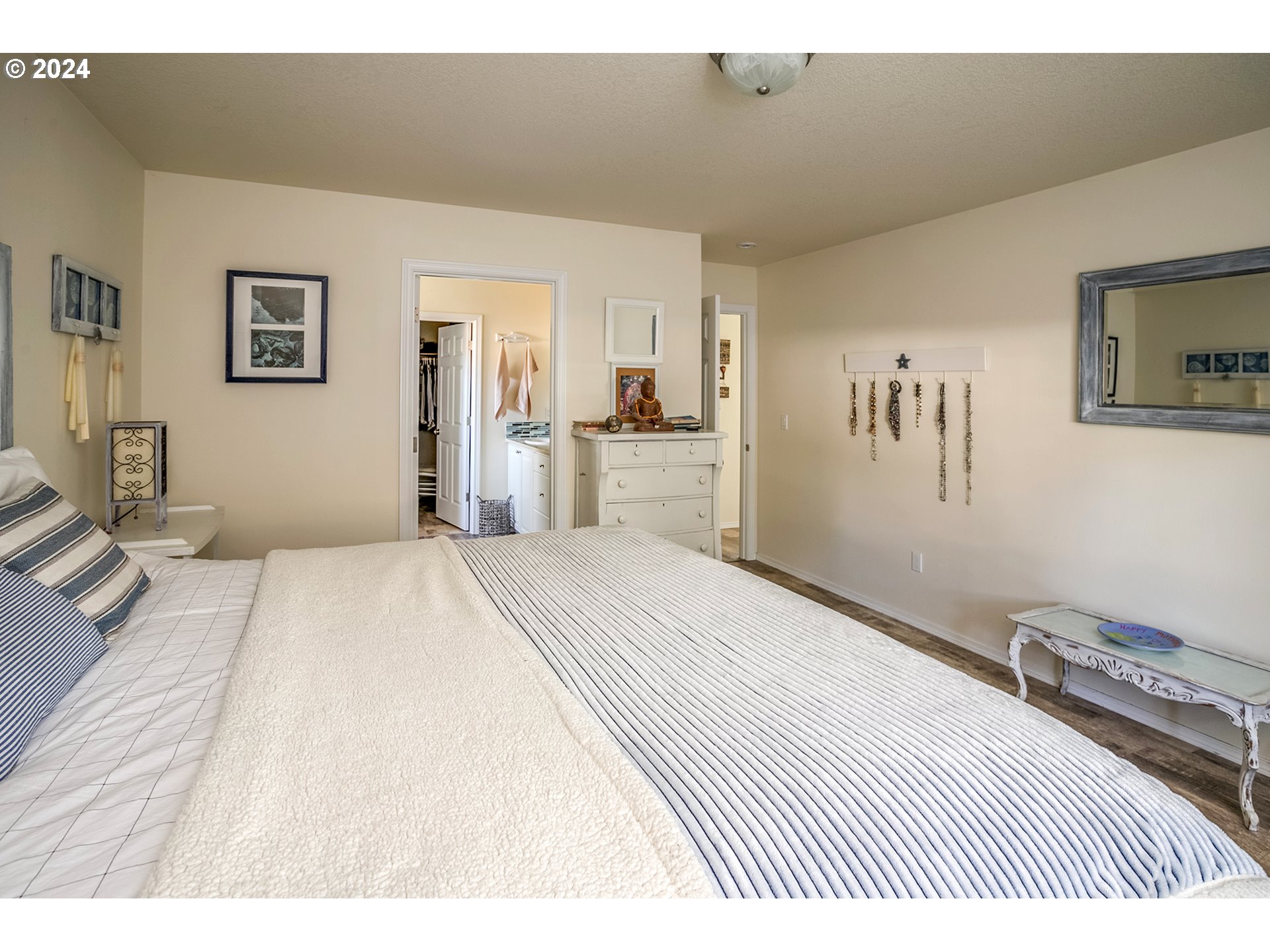 Bedroom with a large striped-bedspread bed and an open doorway to the ensuite bathroom.