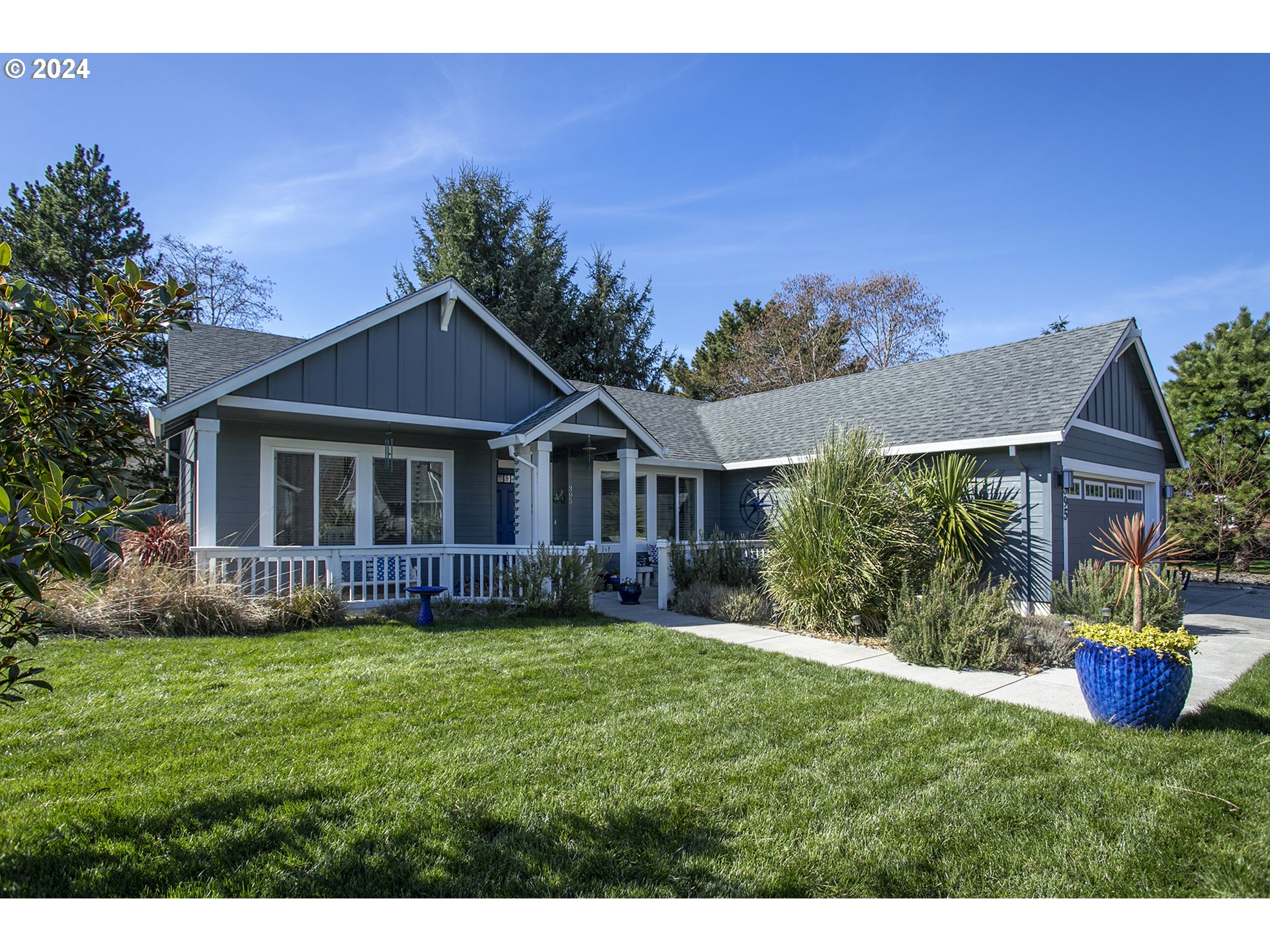 Gray-blue single-story home with a covered porch, attached garage, and landscaped front lawn.
