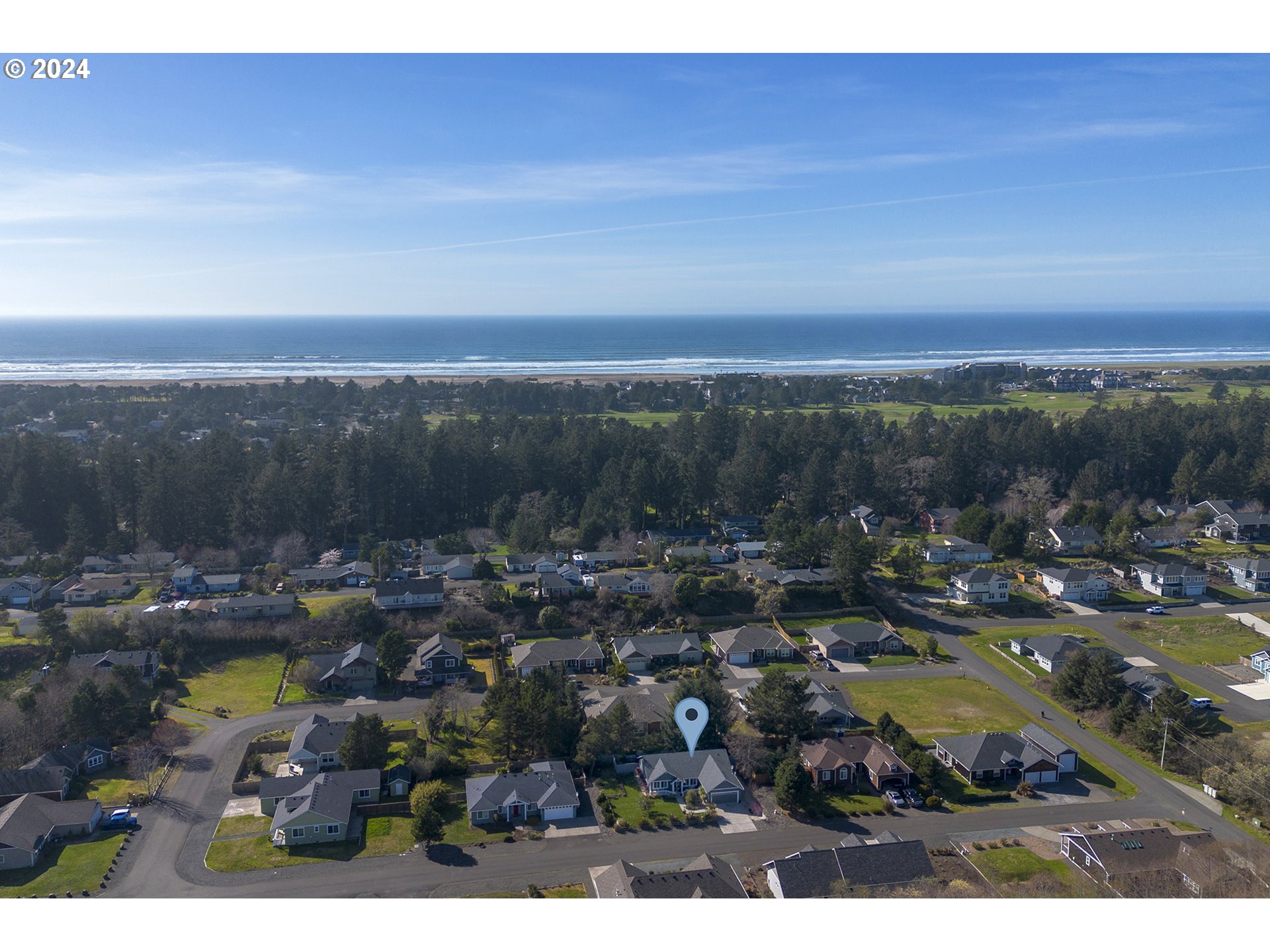 Aerial view of a marked home in a coastal neighborhood, with the ocean and beach in the distance.