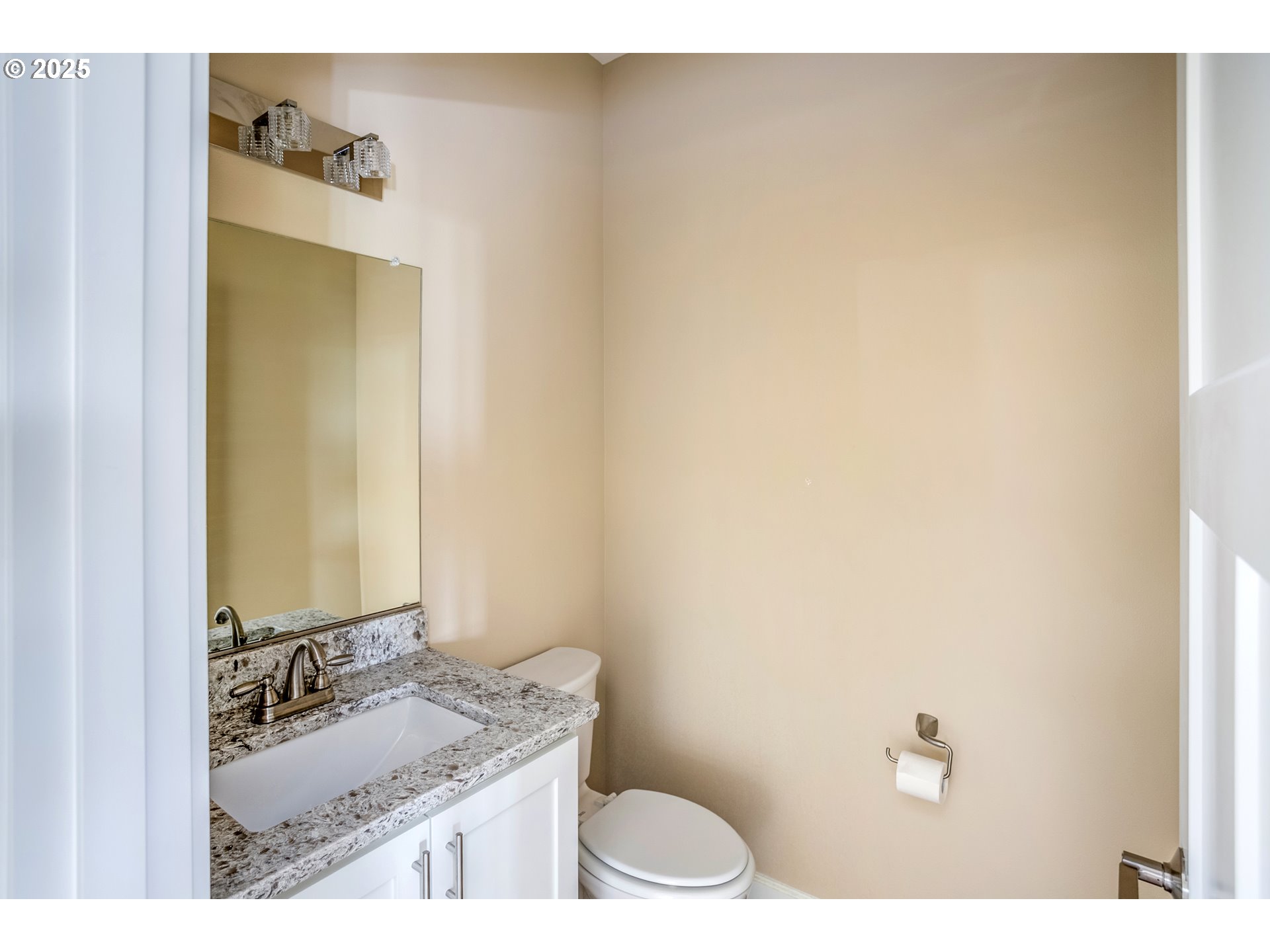 Bathroom with a granite-topped vanity, large mirror, and toilet.