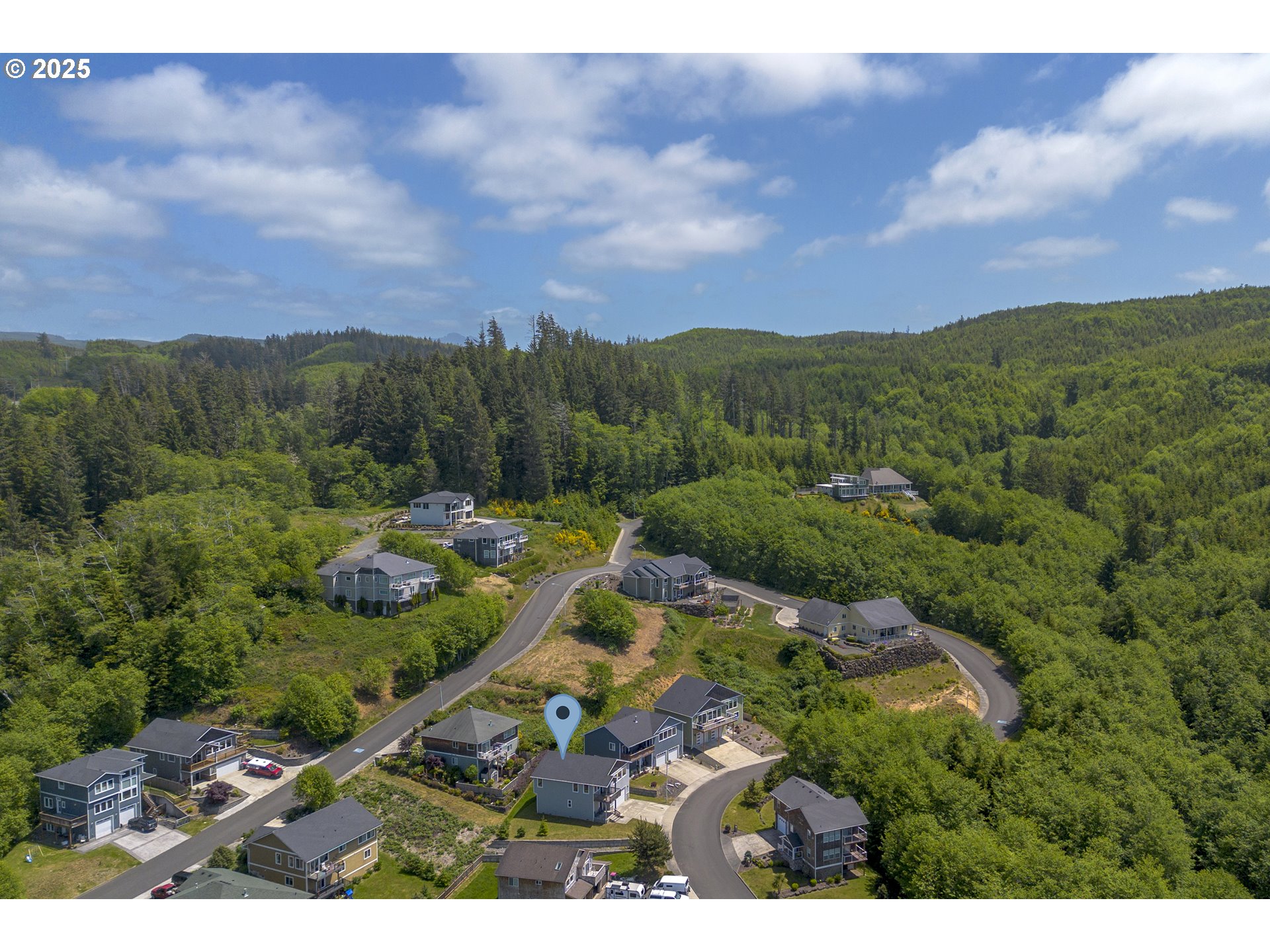 Aerial view of a home in a wooded neighborhood, marked by a blue location pin.