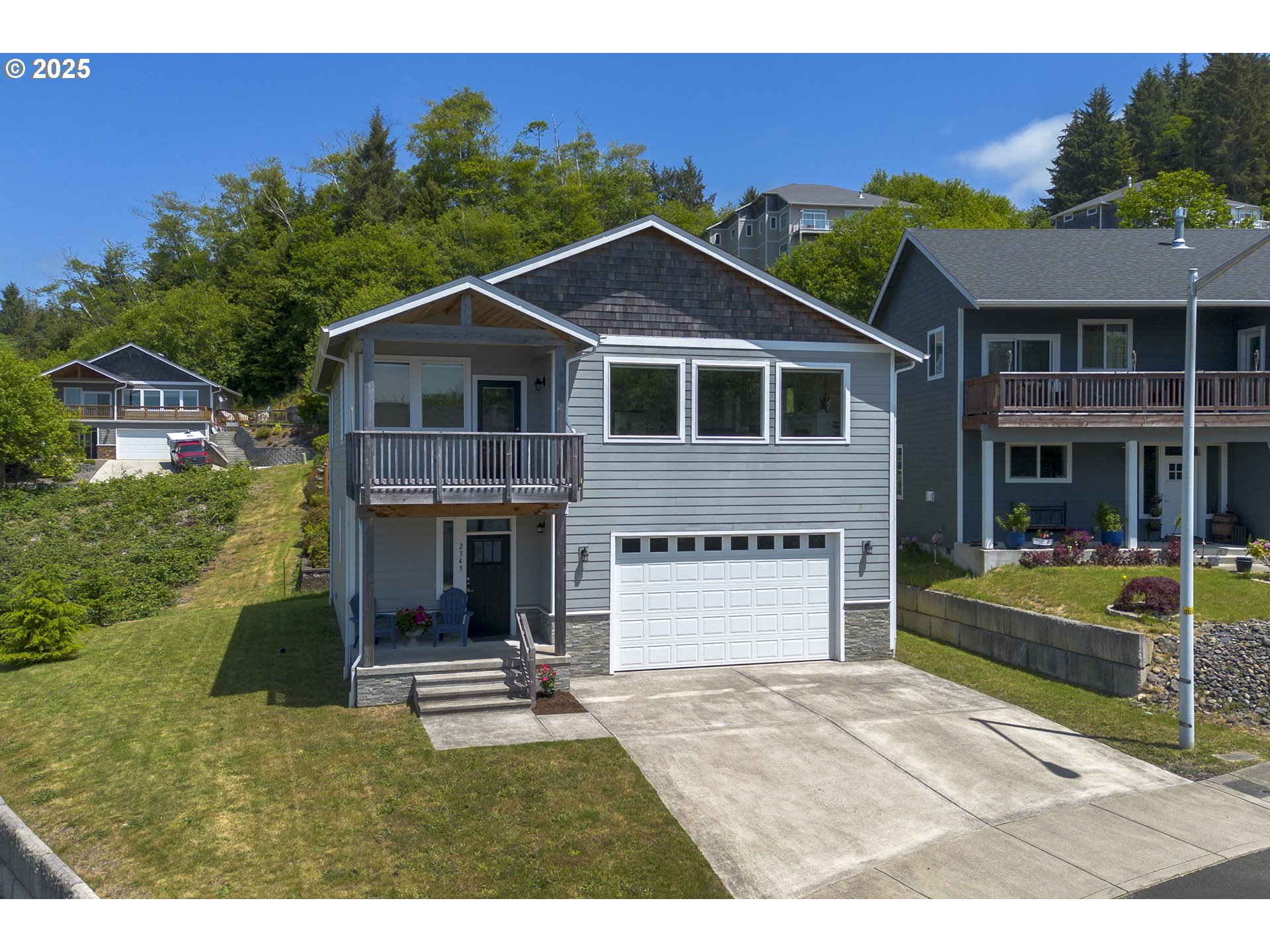 Gray two-story house with an upper balcony, covered porch, and wide driveway.