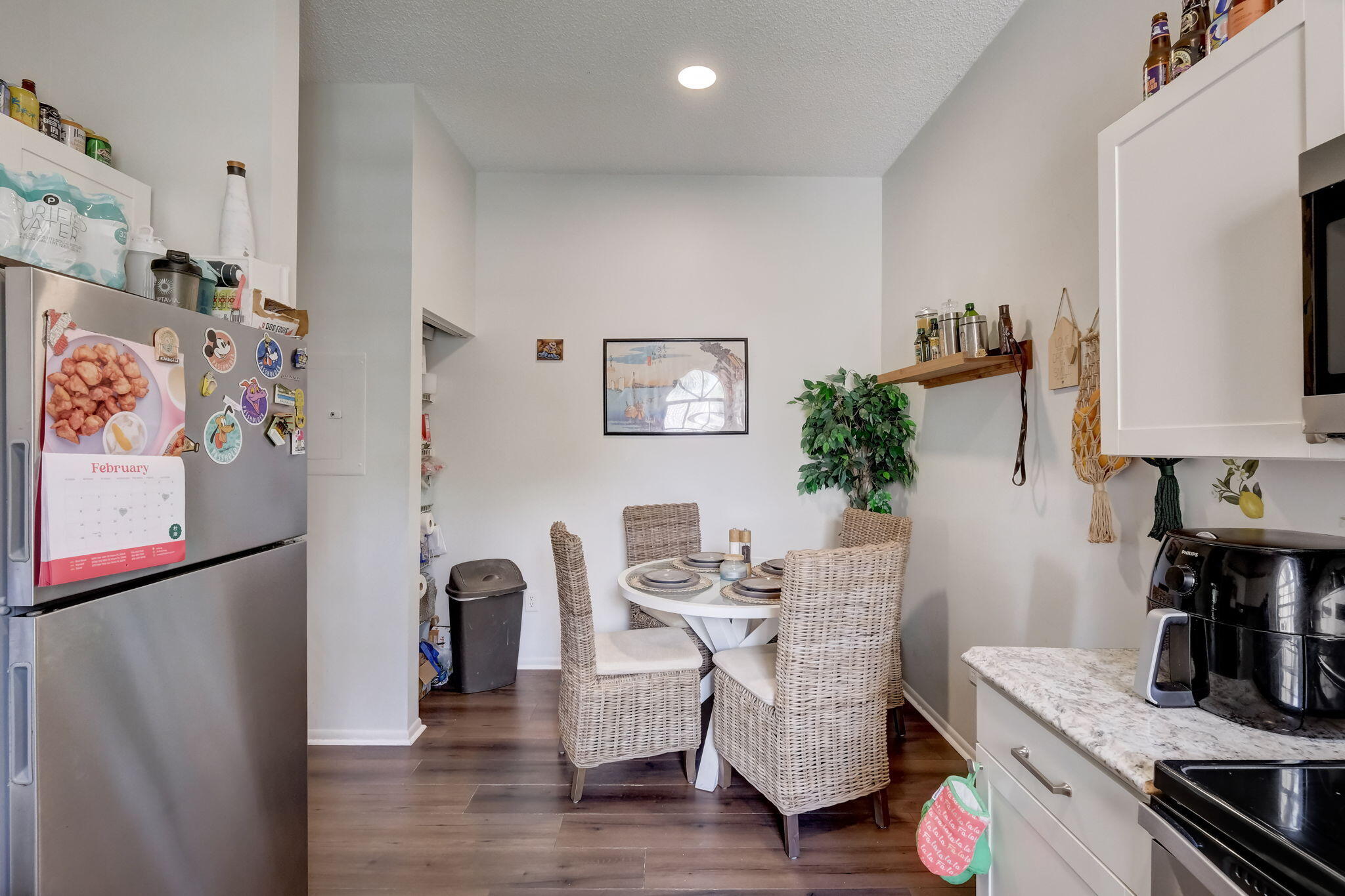 Kitchen dining area with a round table, wicker chairs, and a magnet-covered refrigerator.