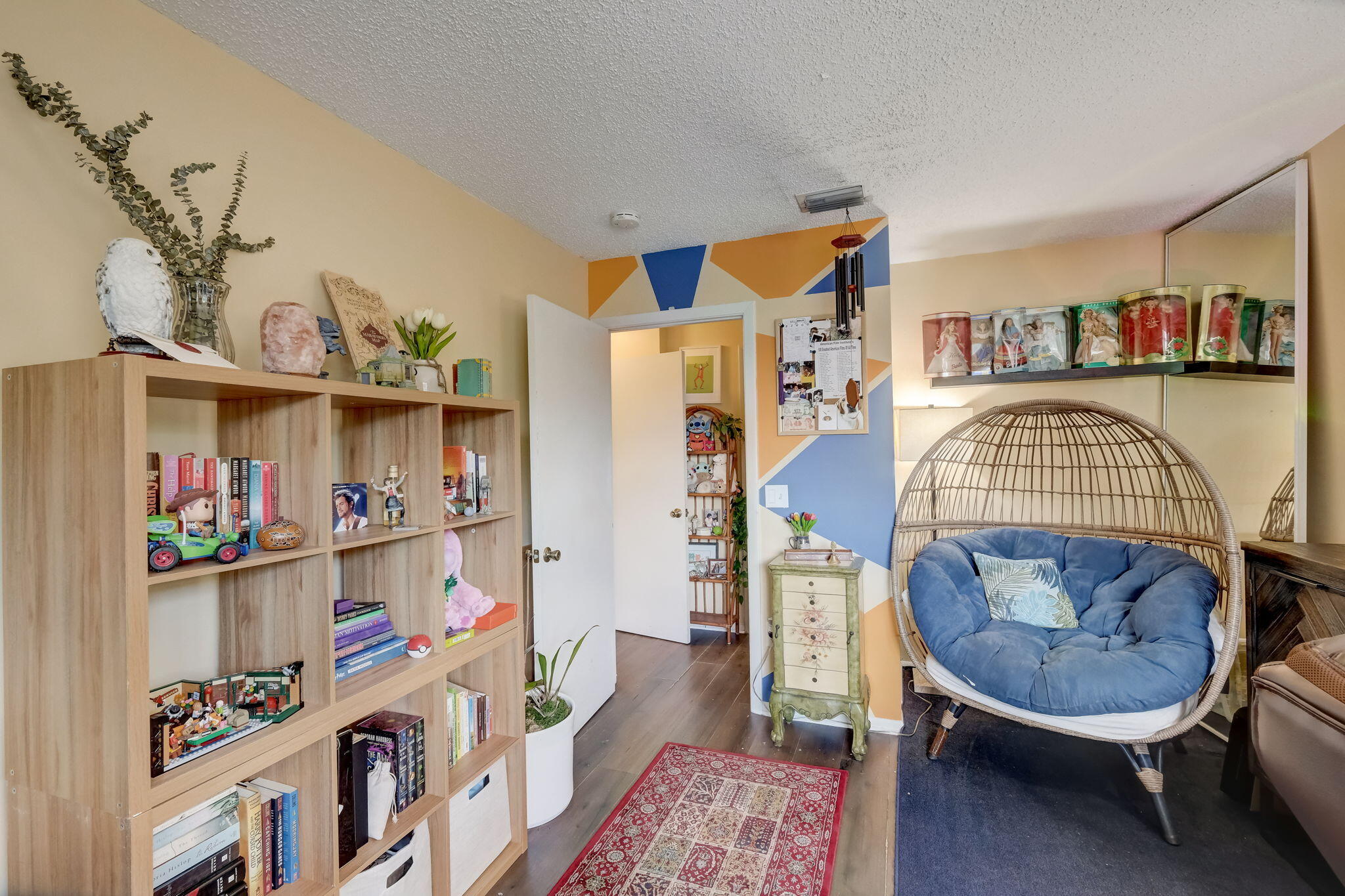 Sitting room with wooden bookshelves and a blue-cushioned wicker egg chair.