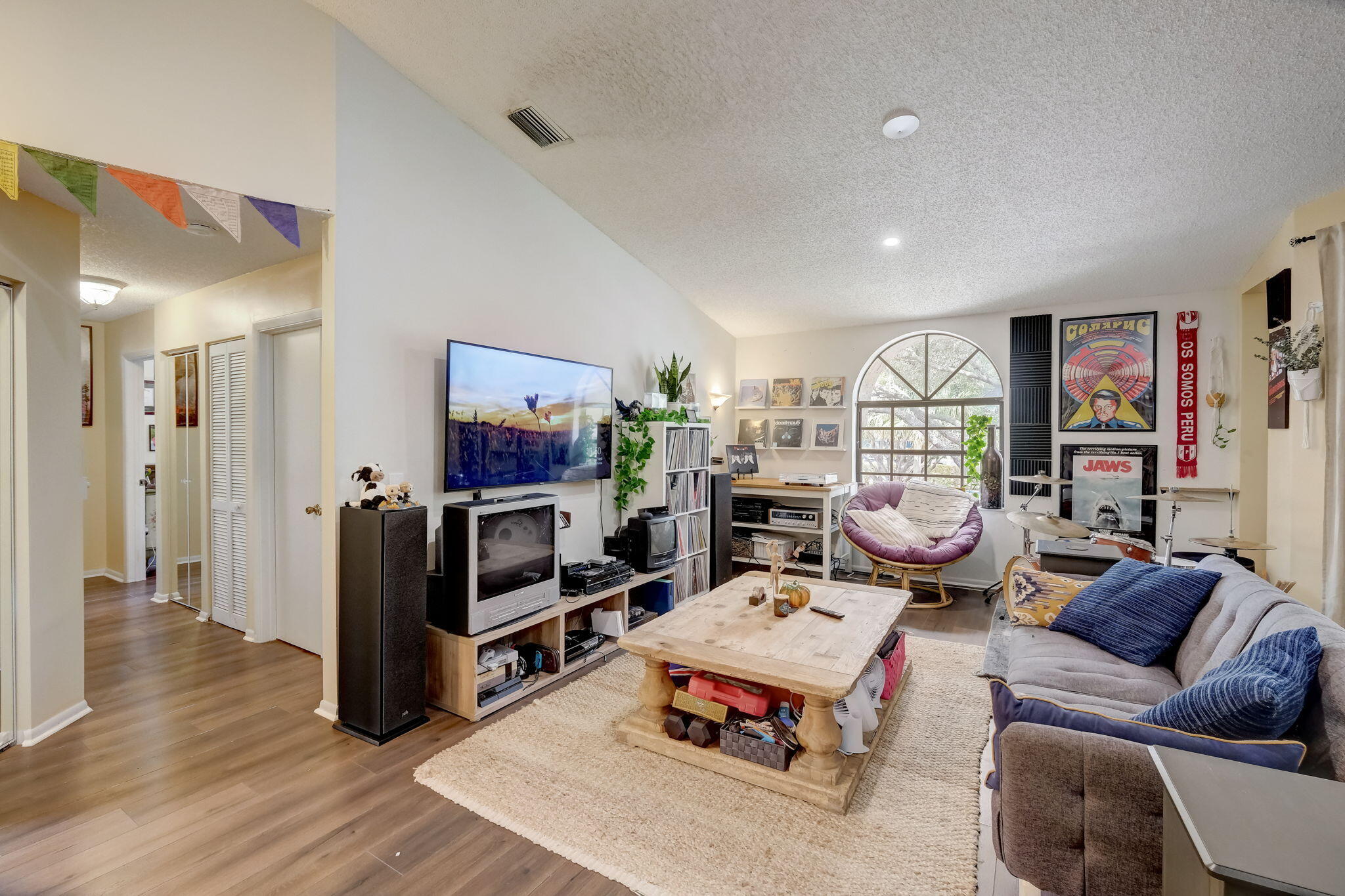 Furnished living room with a large arched window, gray sofa, and wooden coffee table.