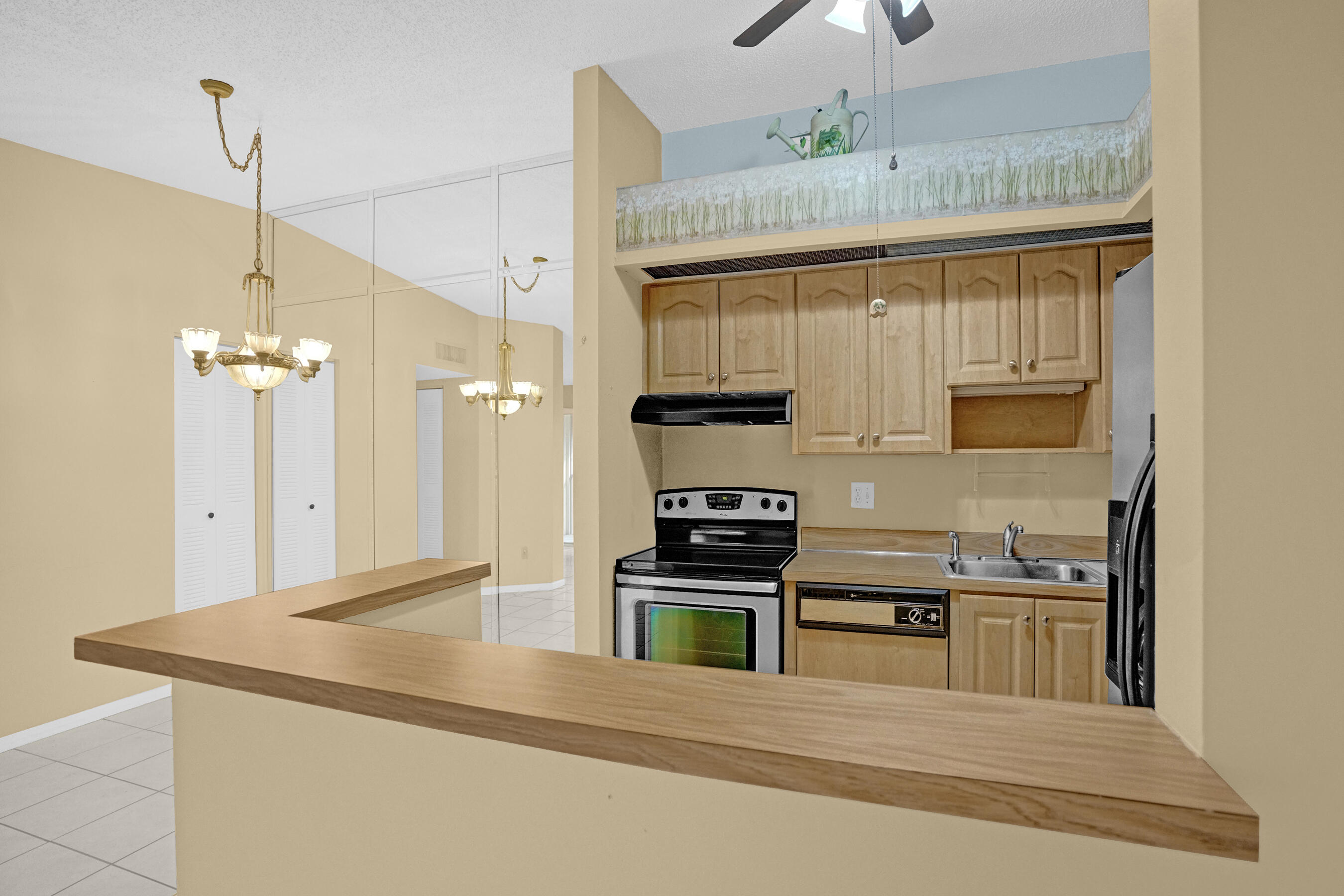 Kitchen with light wood cabinets, black range, stainless sink, and a long breakfast bar.