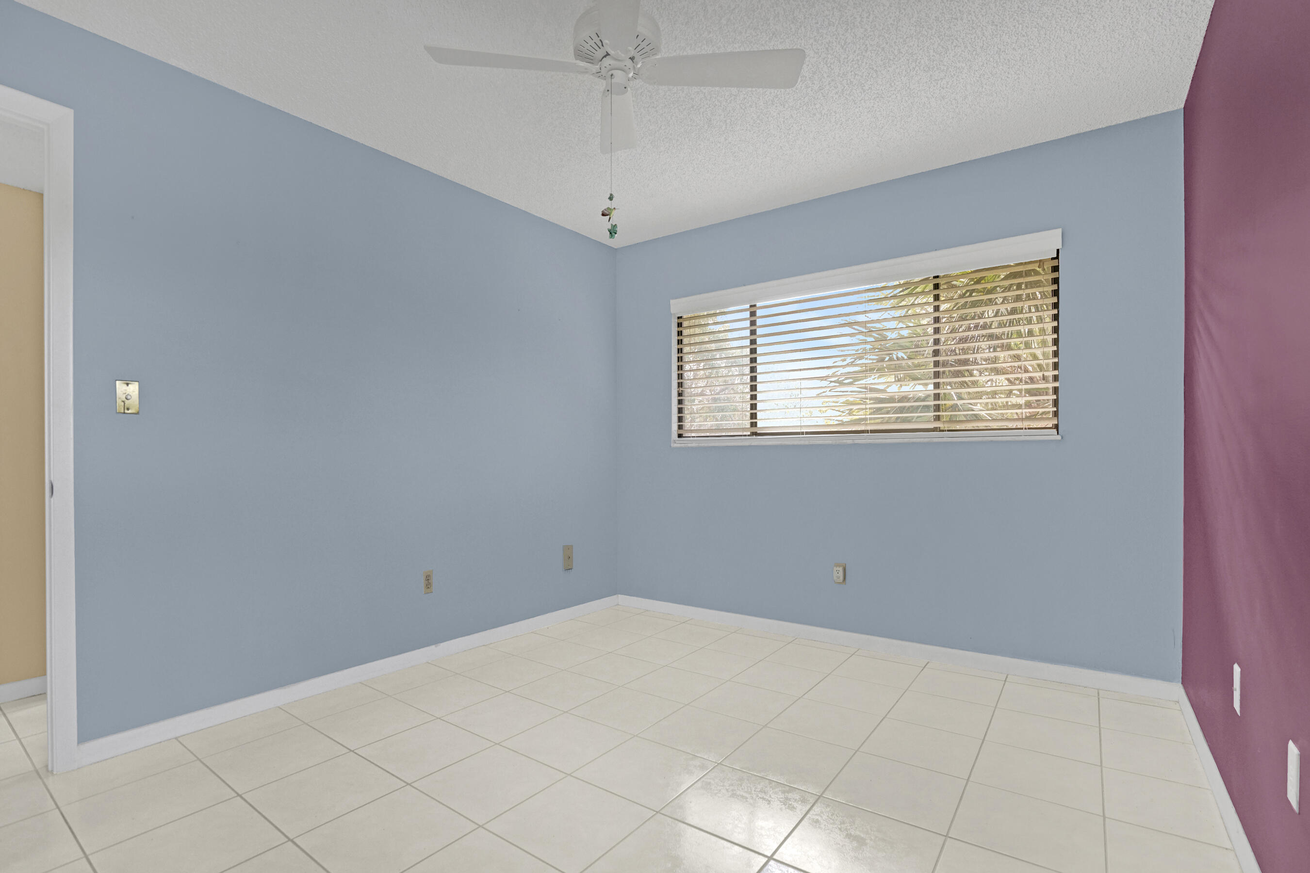 Unfurnished room with blue and purple walls, tiled floors, and a window with blinds.